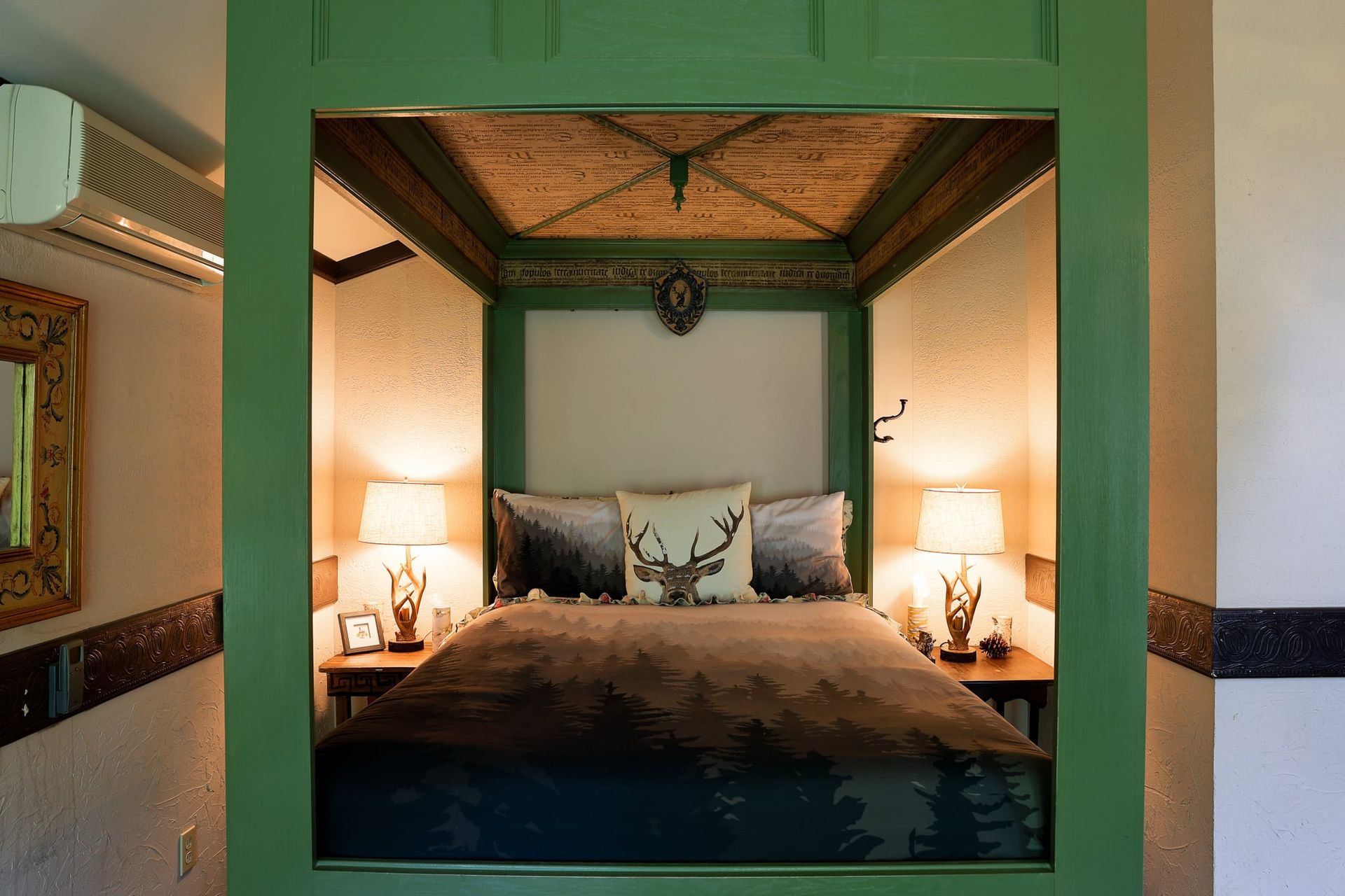 A bed with a deer pillow is sitting under a canopy in a bedroom.
