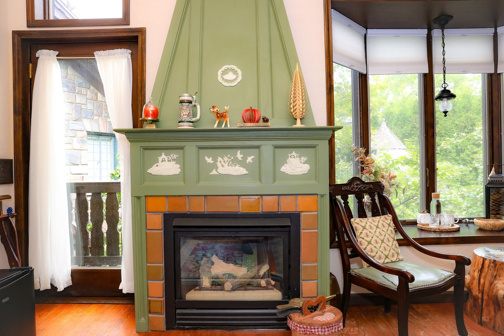 A living room with a green fireplace and a chair.