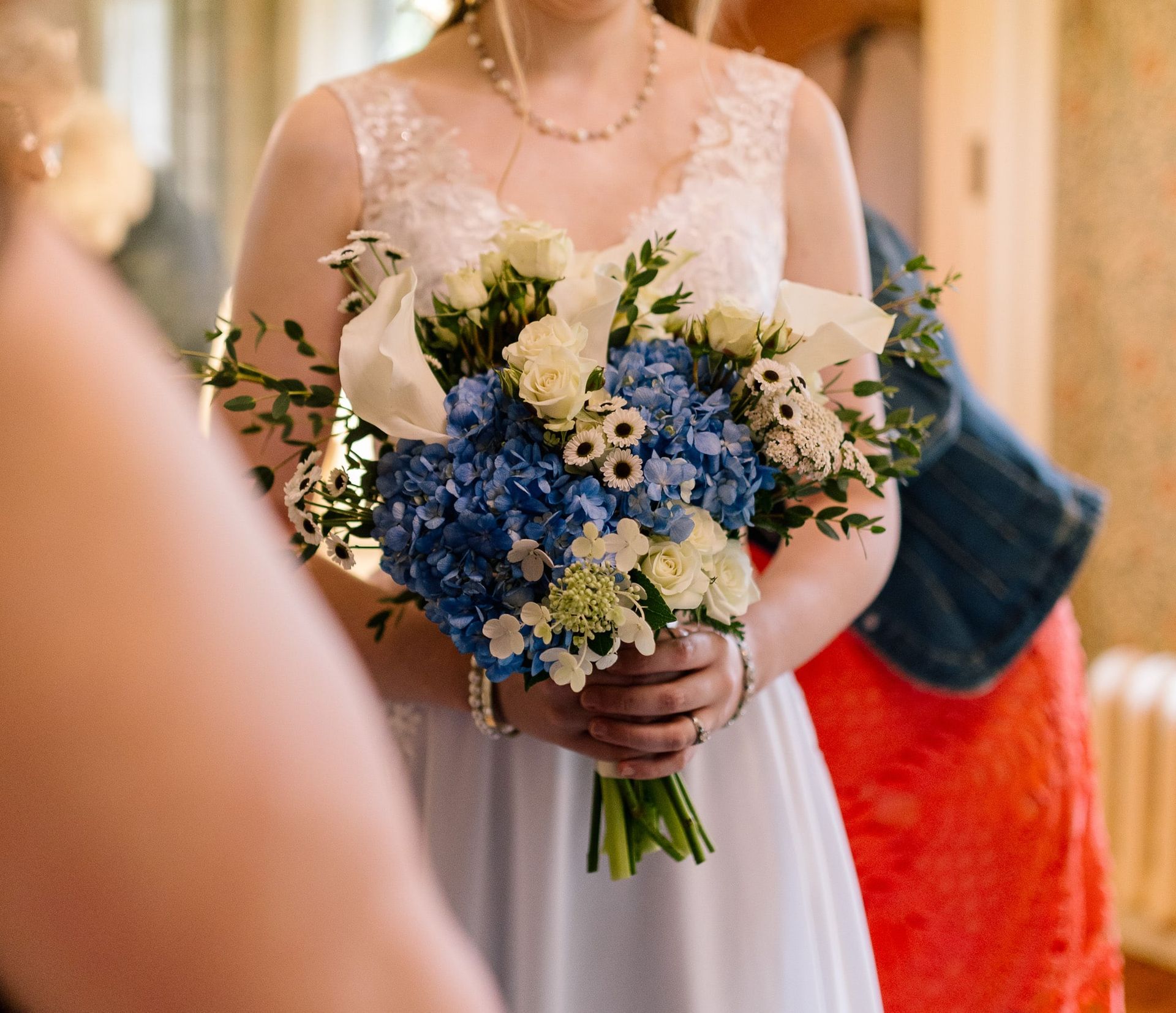 A woman in a white dress is holding a bouquet of blue and white flowers.