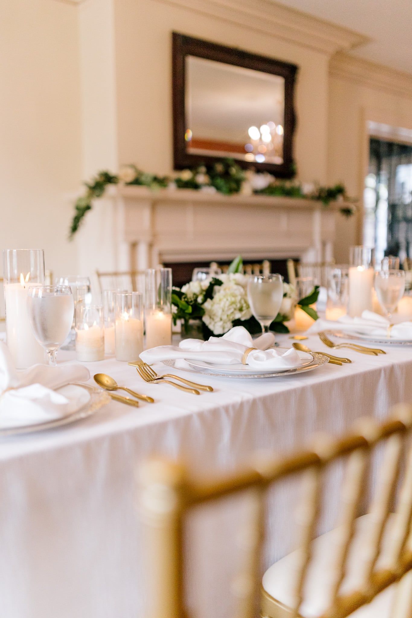 A long table with plates , silverware , candles and flowers on it.