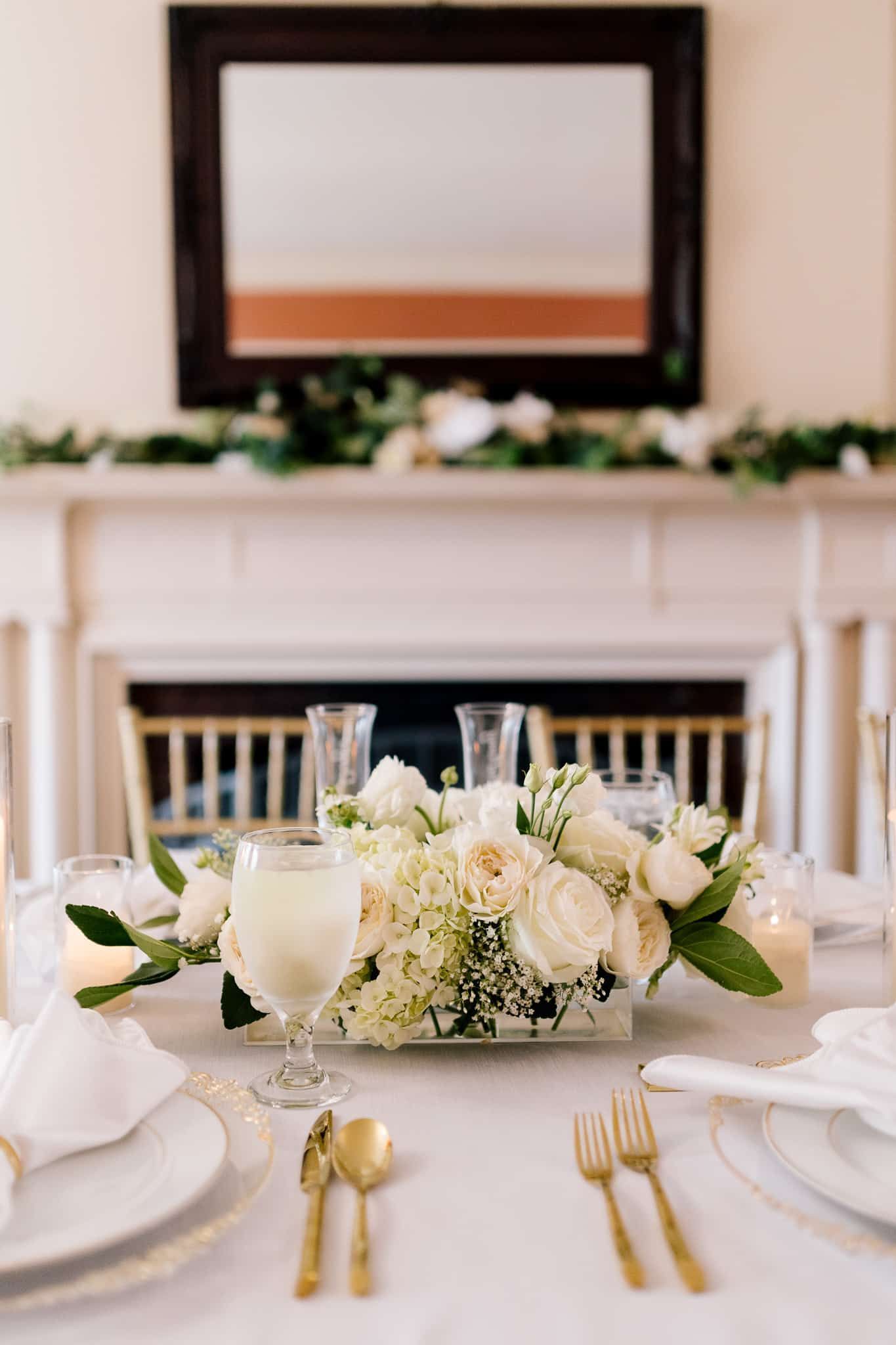 A table set for a wedding reception with a vase of flowers on it.