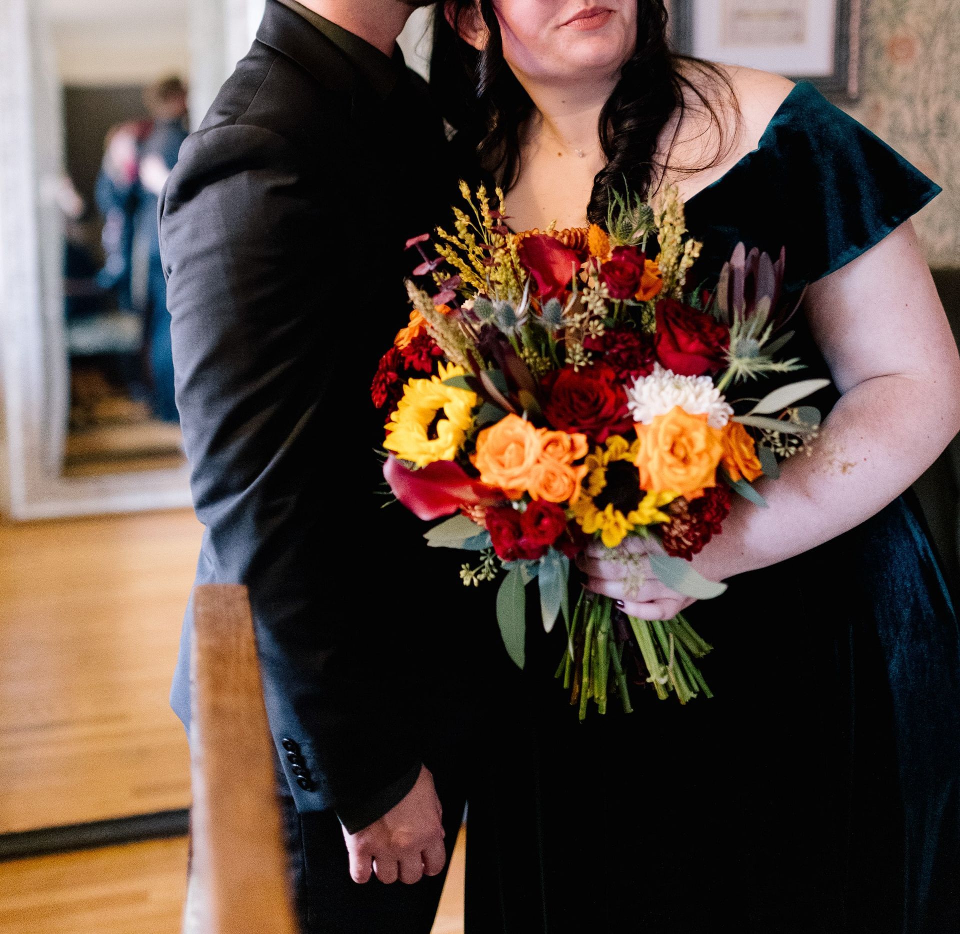 A man is kissing a woman who is holding a bouquet of flowers.