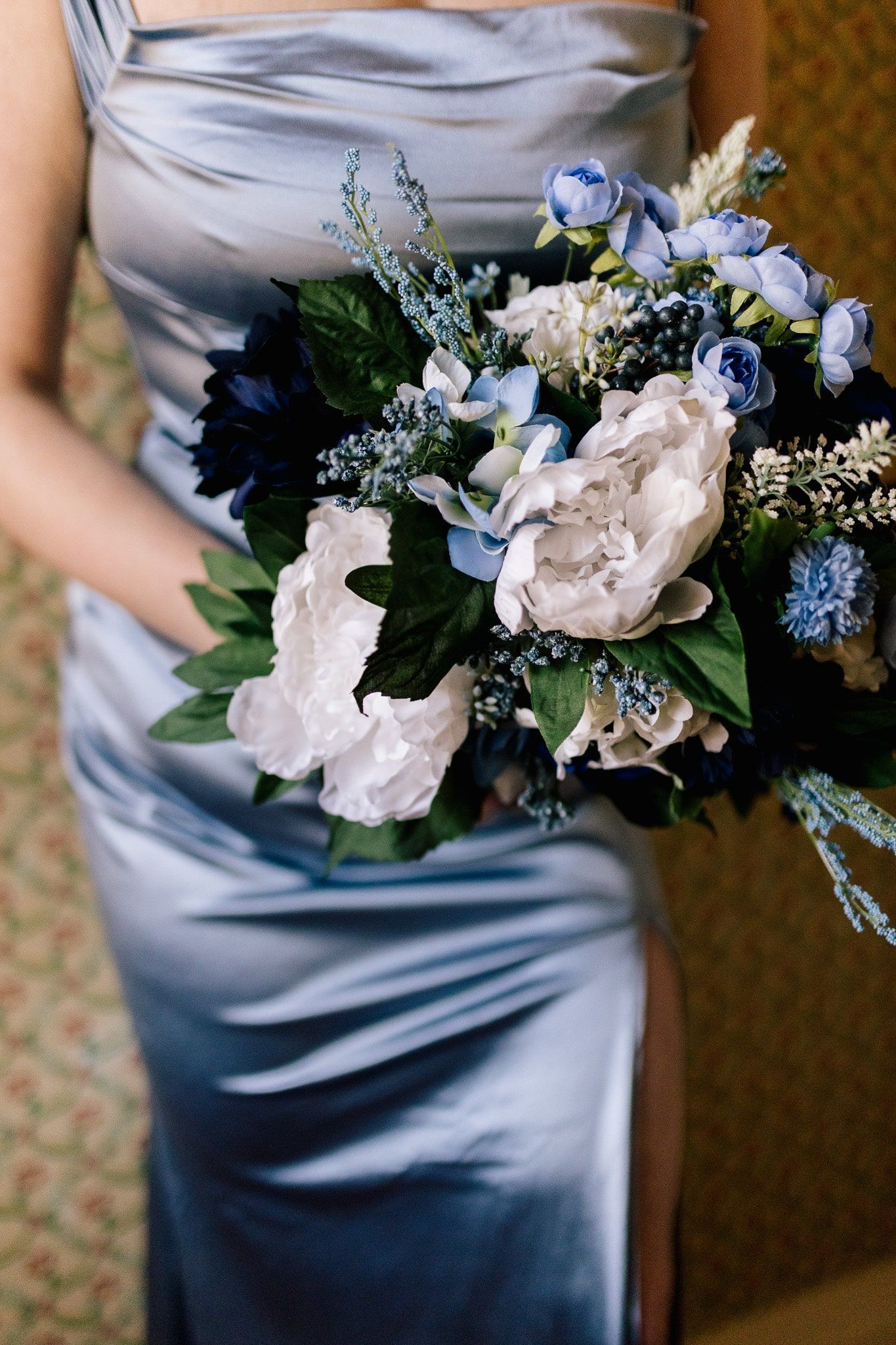 A woman in a blue dress is holding a bouquet of flowers.