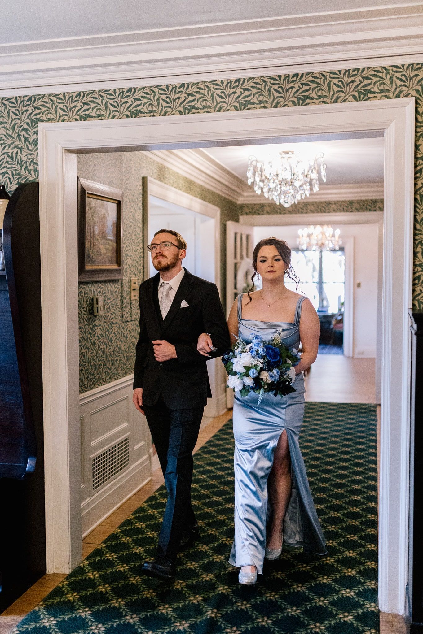 A bride and groom are walking down a hallway.