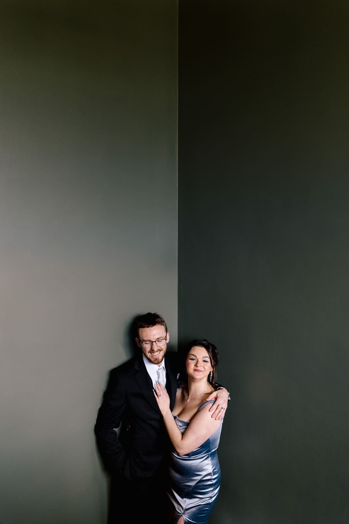 A man and a woman are standing next to each other in front of a wall.