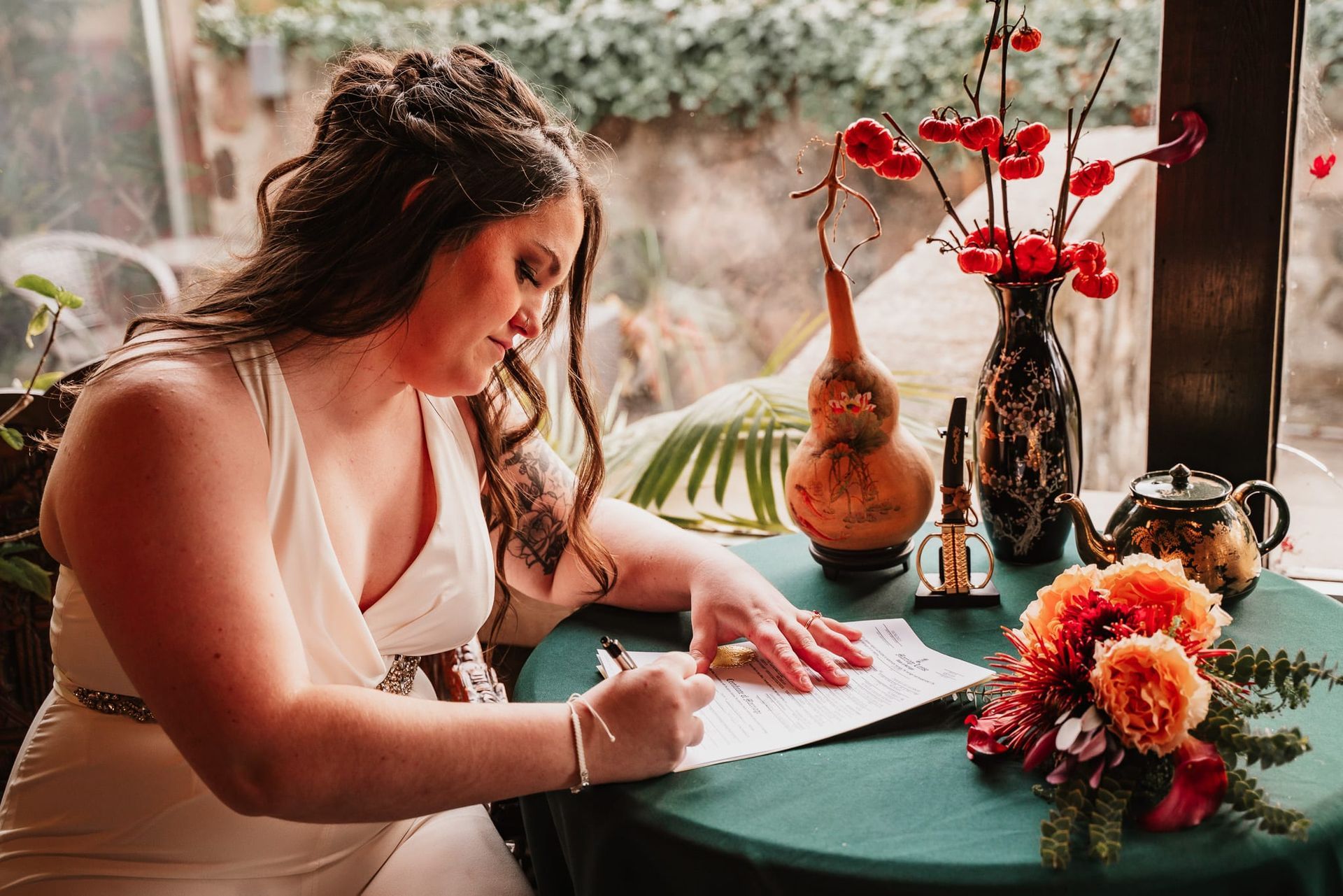 A woman is sitting at a table signing a document.
