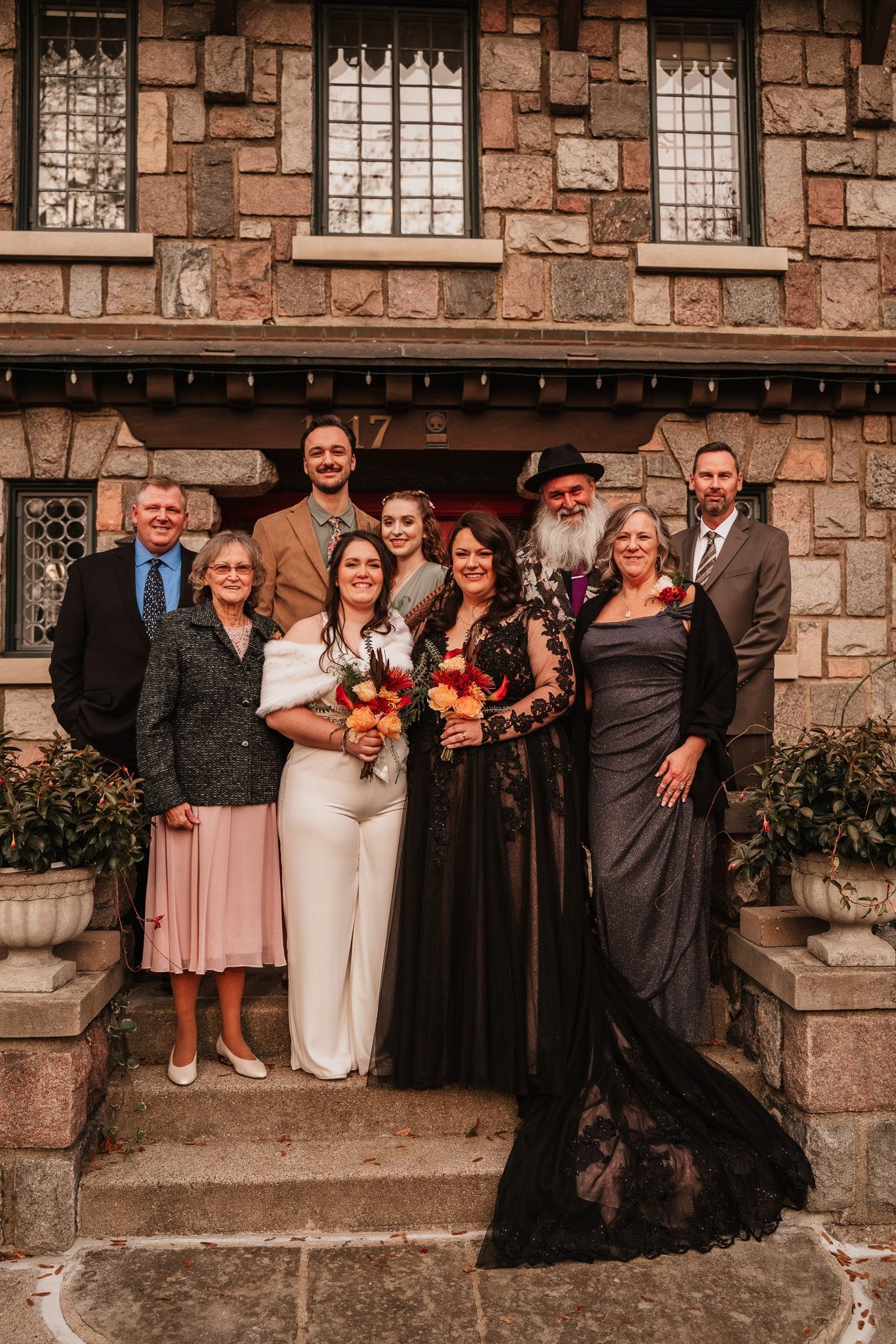 A group of people are posing for a picture in front of a stone building.