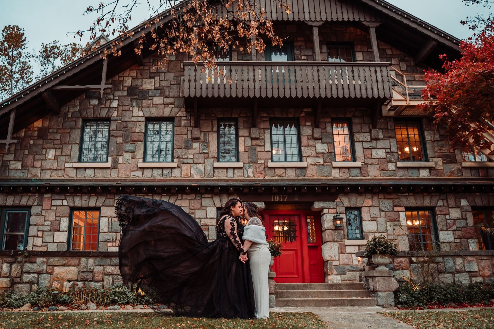 A bride and groom are kissing in front of a large stone building.