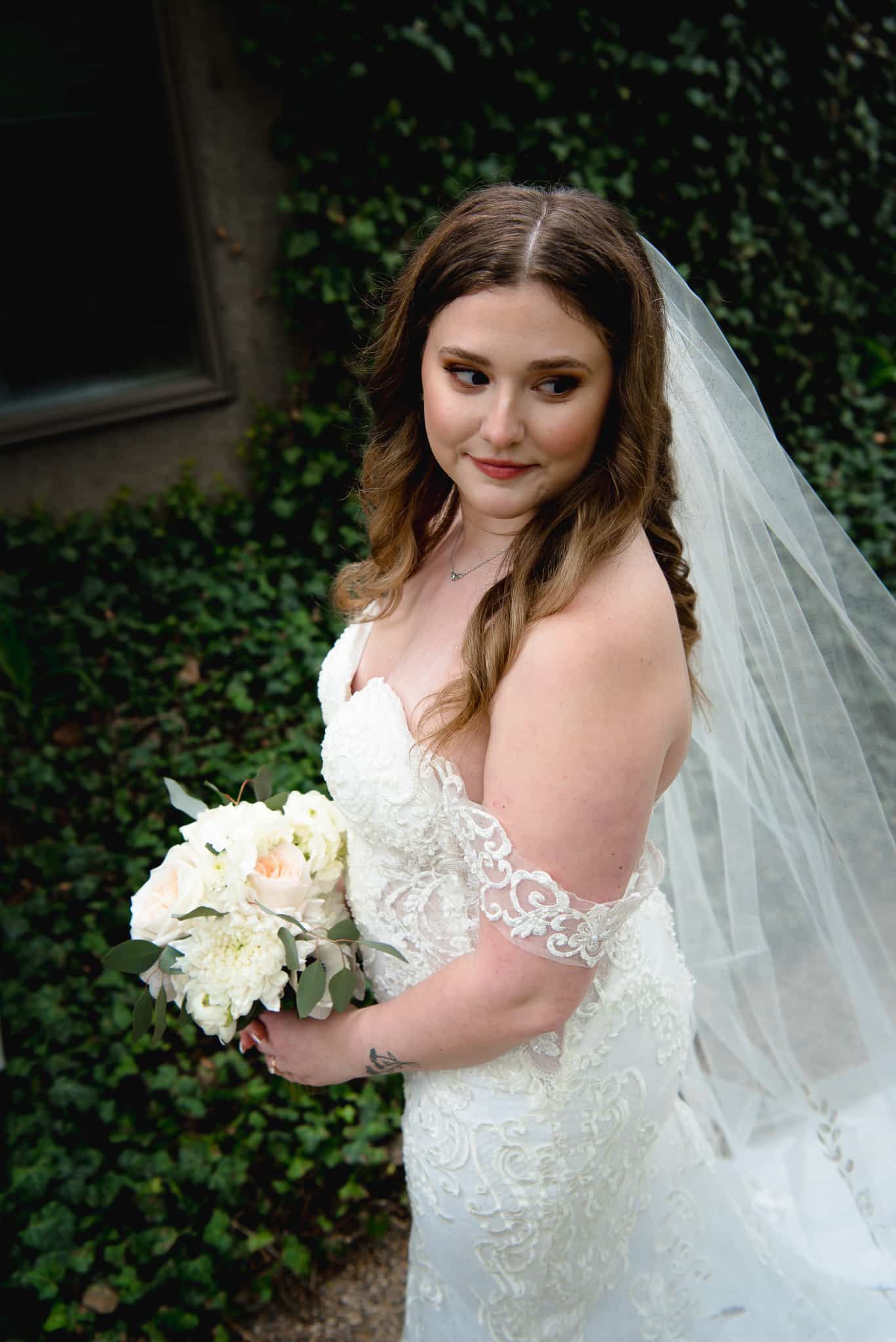 A bride in a wedding dress and veil is holding a bouquet of flowers.