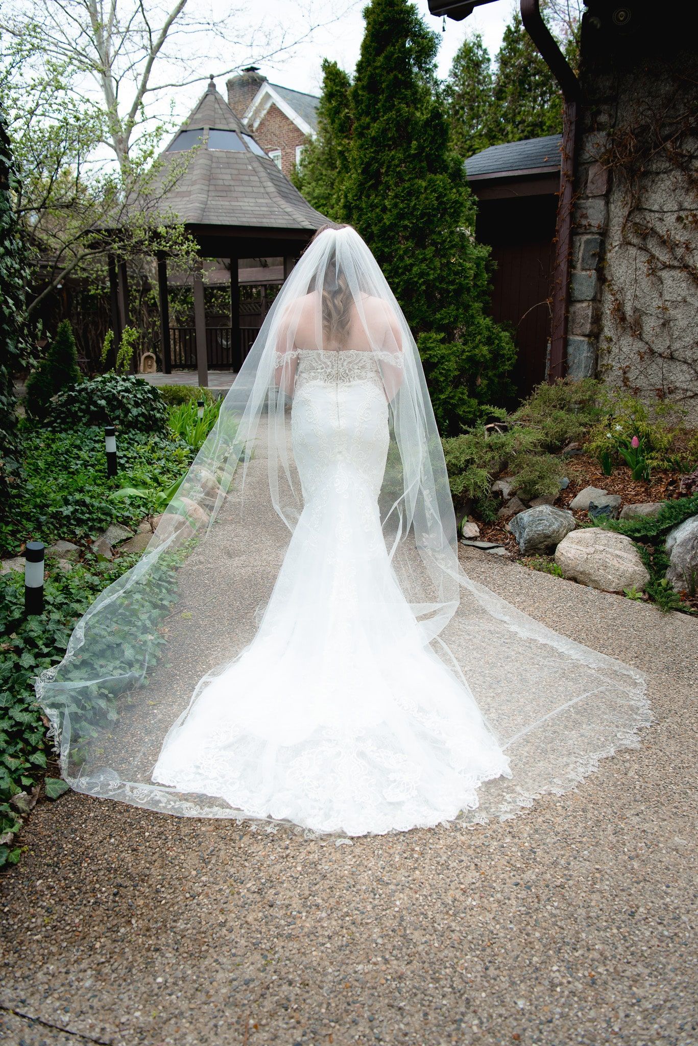 The bride is wearing a long veil and a wedding dress.
