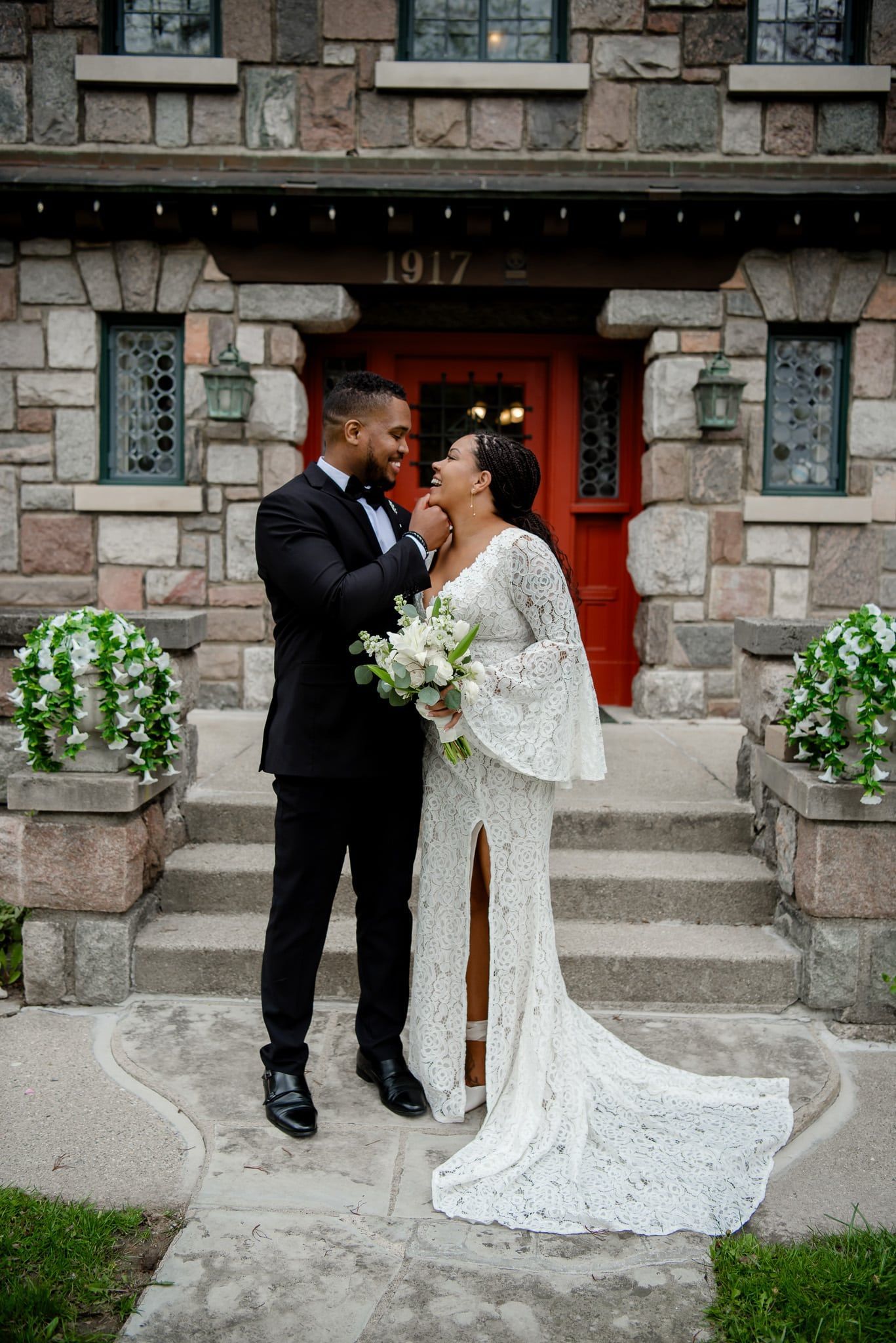 A bride and groom are posing for a picture in front of a stone building.