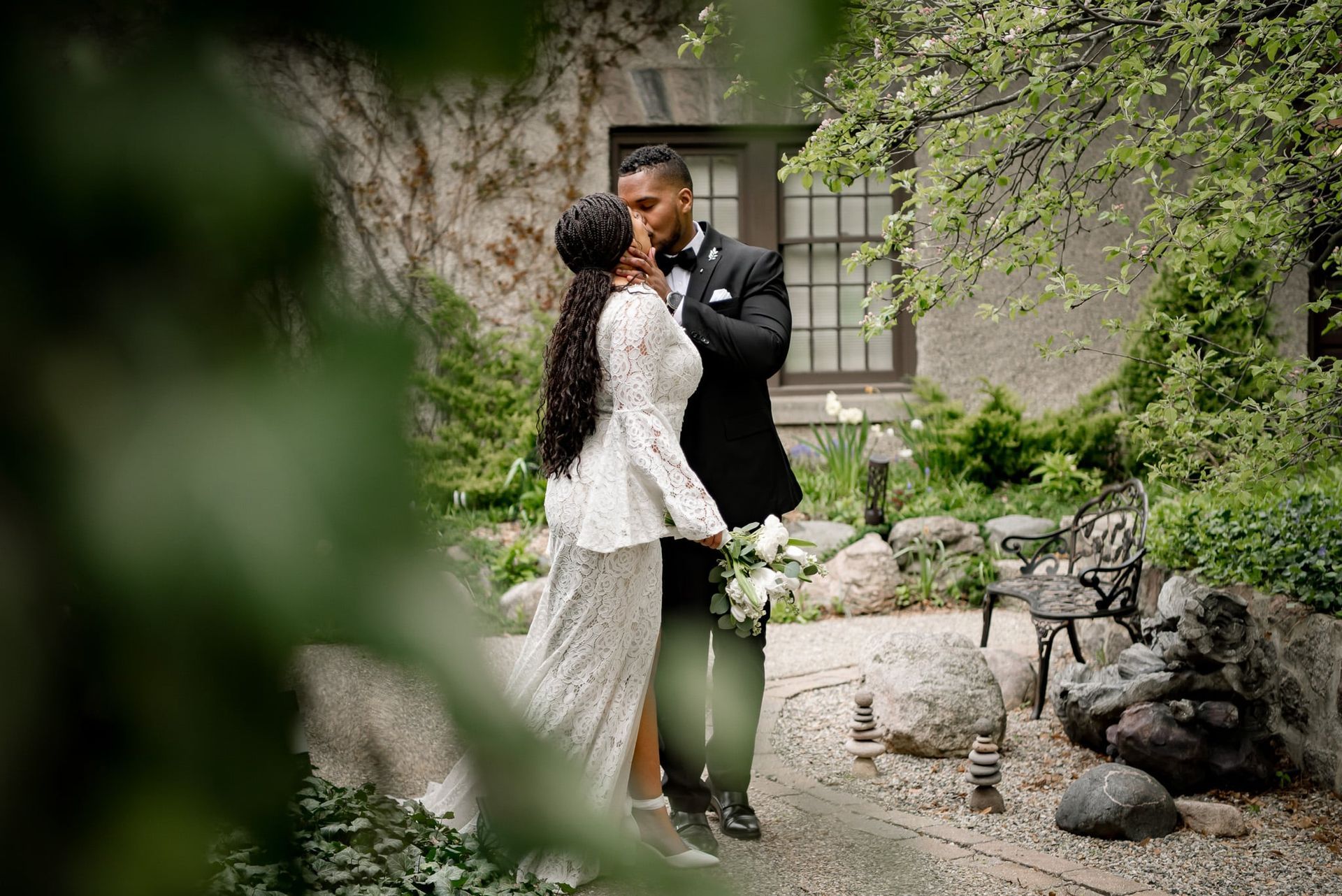 A bride and groom are kissing in front of a building.