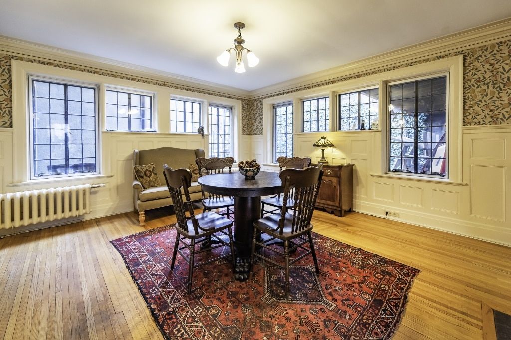 A dining room with a table and chairs and a rug.