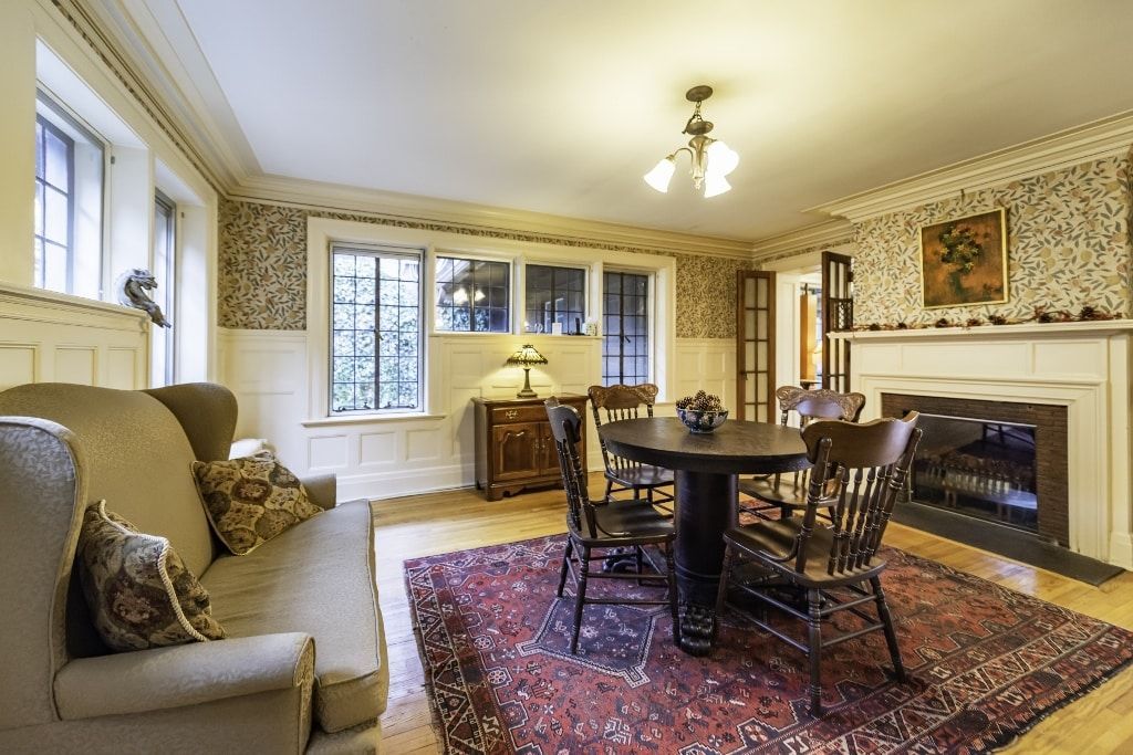 A living room with a couch , chairs , table and fireplace.