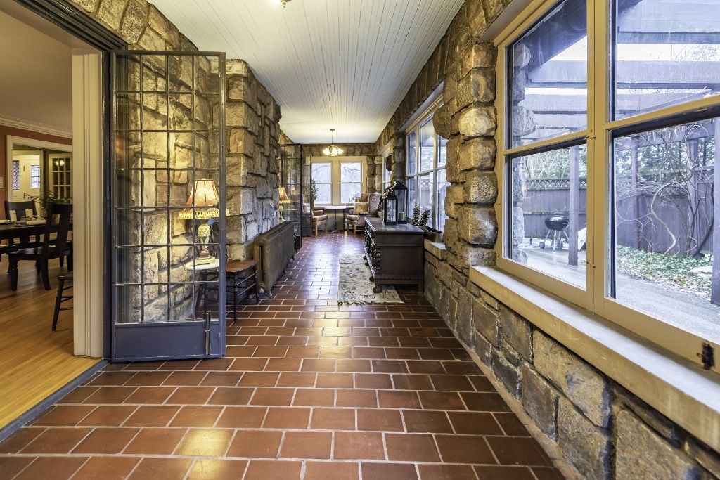 A long hallway with brick floors and windows in a house.