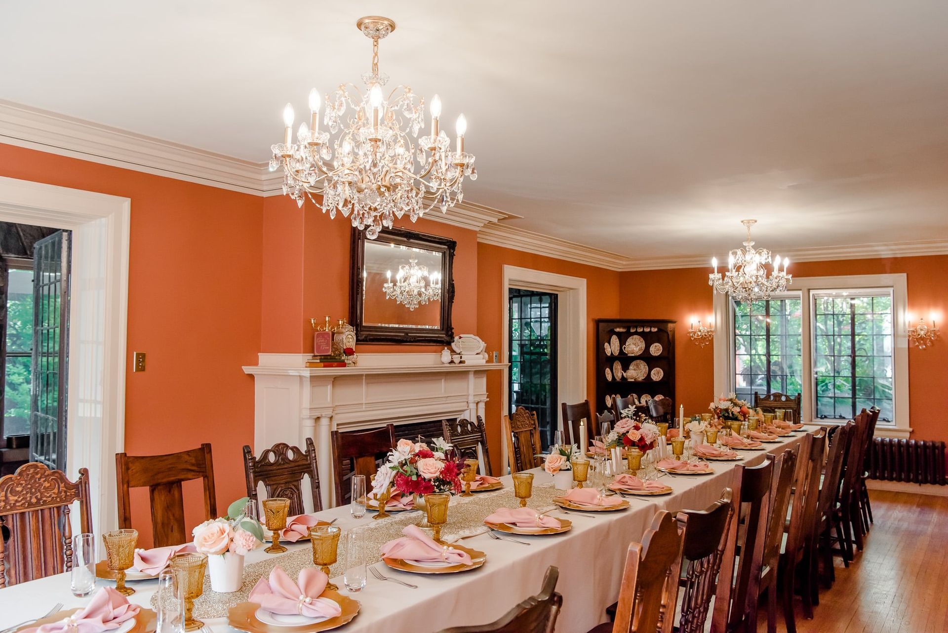 There is a long table with plates and glasses on it in the dining room.