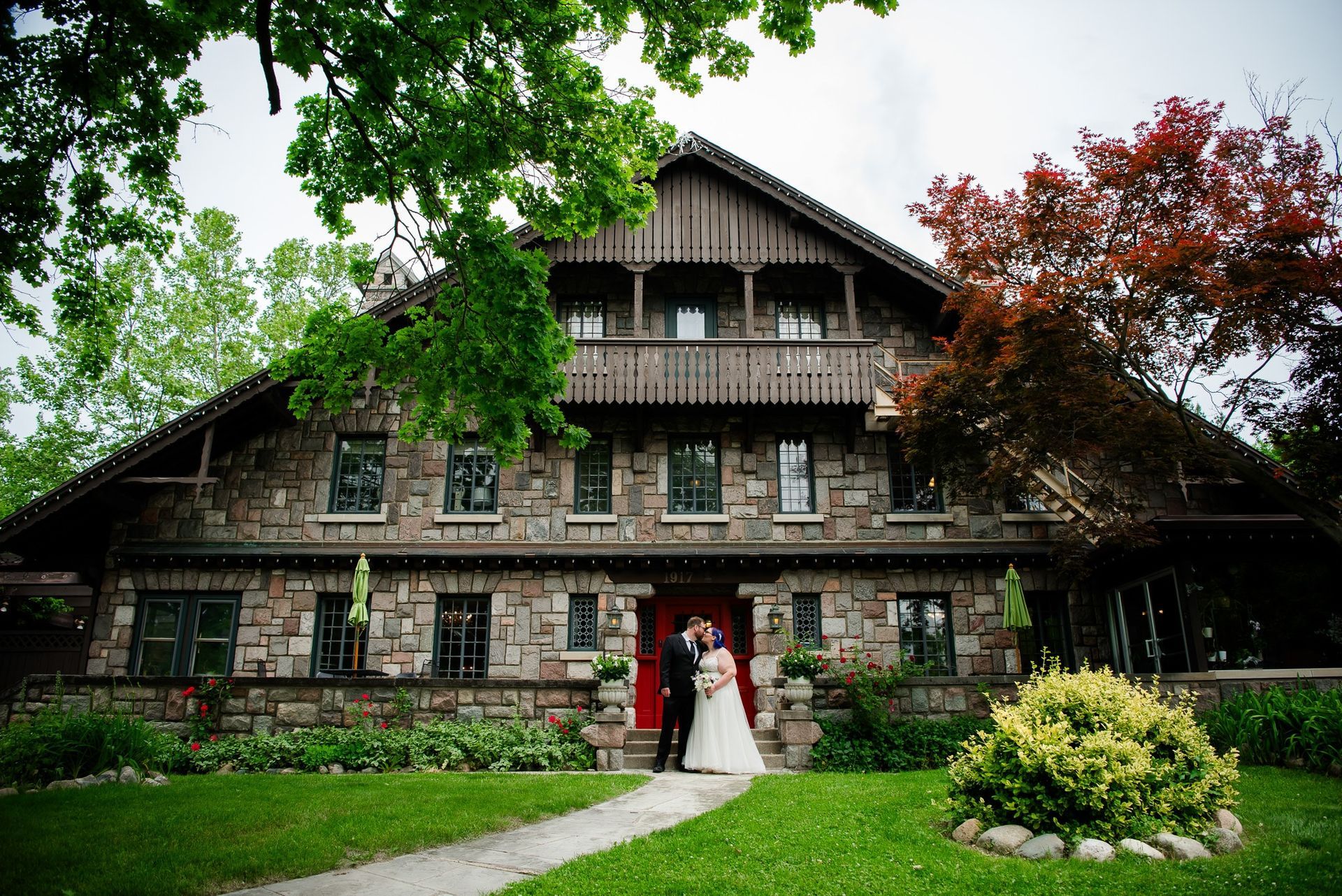 A bride and groom are standing in front of a large stone building.