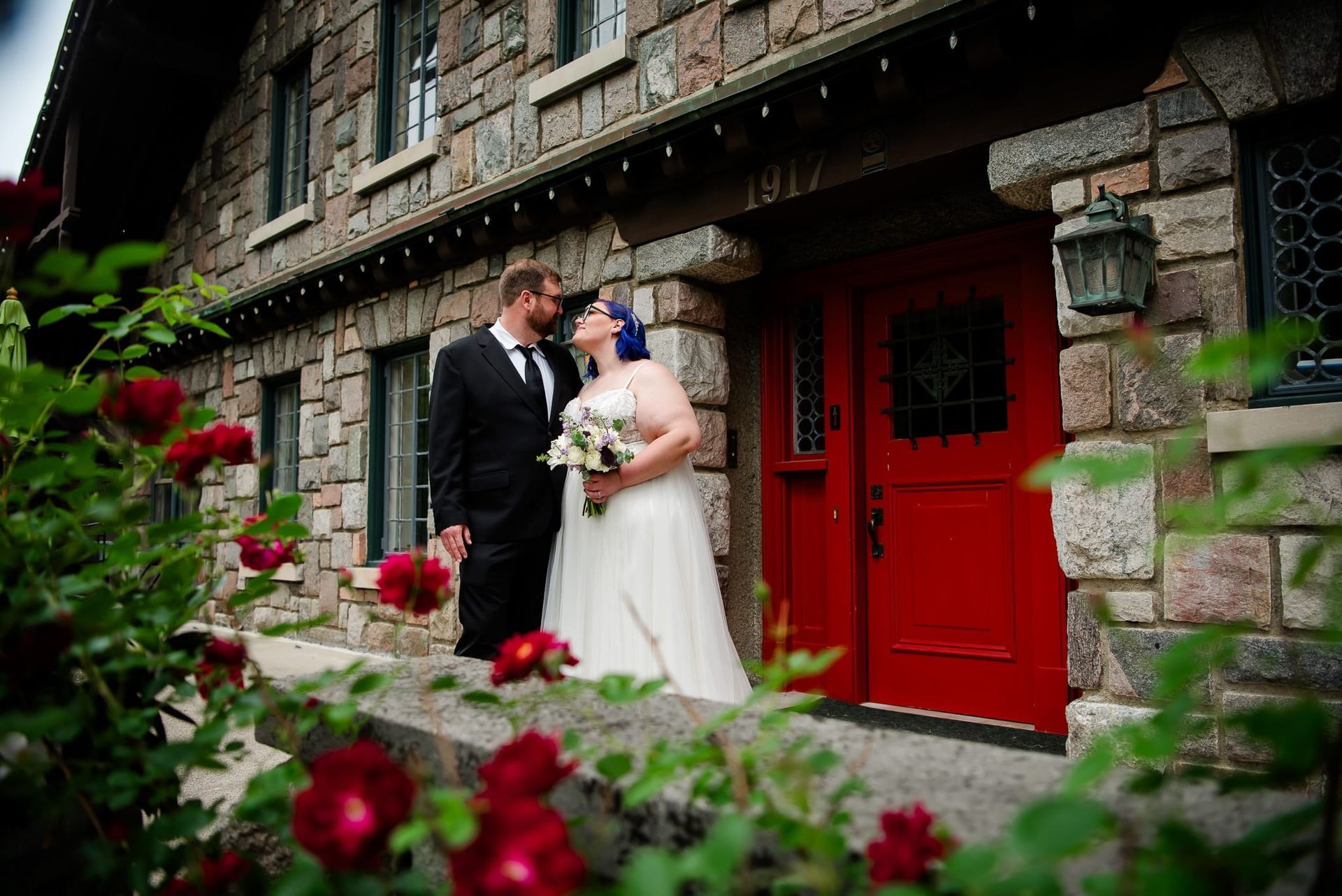 A bride and groom are posing for a picture in front of a red door.