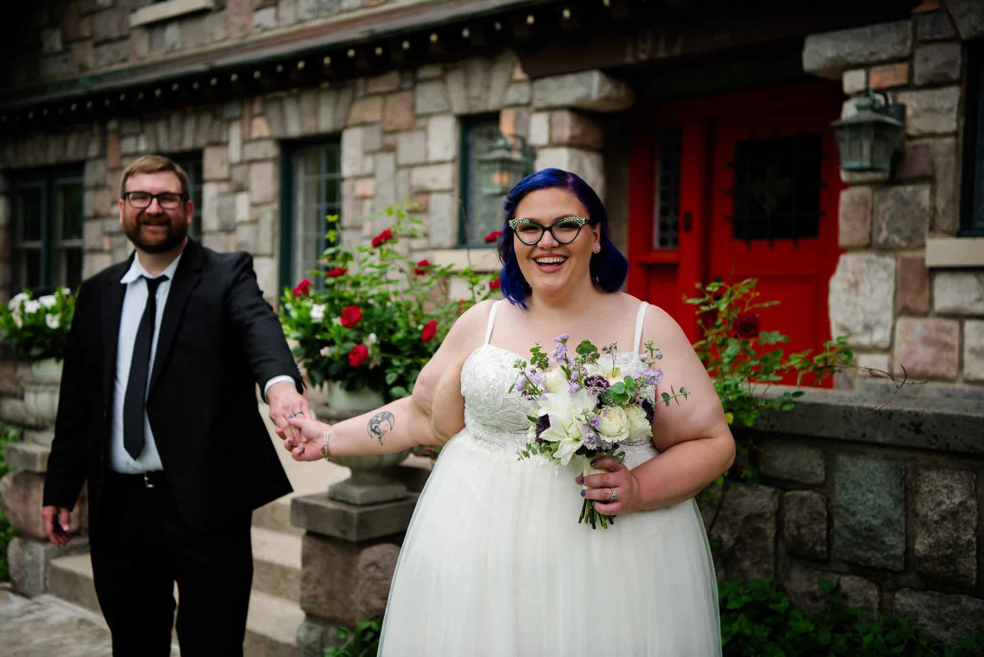 A bride and groom are holding hands in front of a brick building.