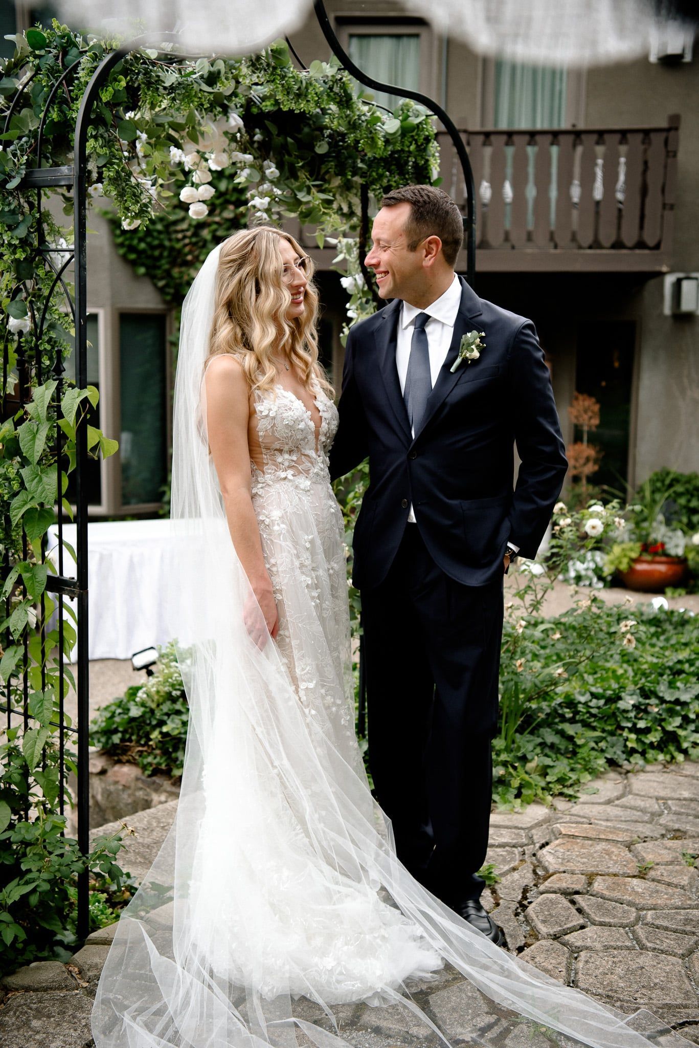 A bride and groom are standing next to each other in a garden.