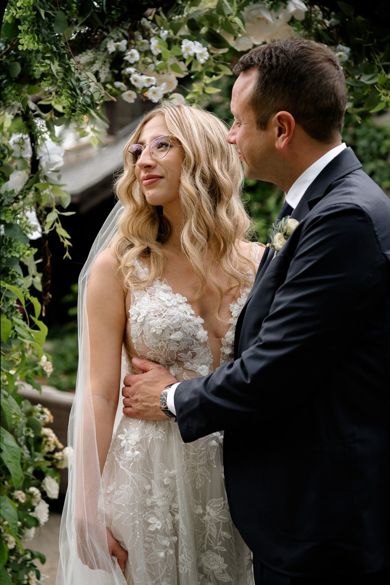 A bride and groom are standing next to each other in a garden.