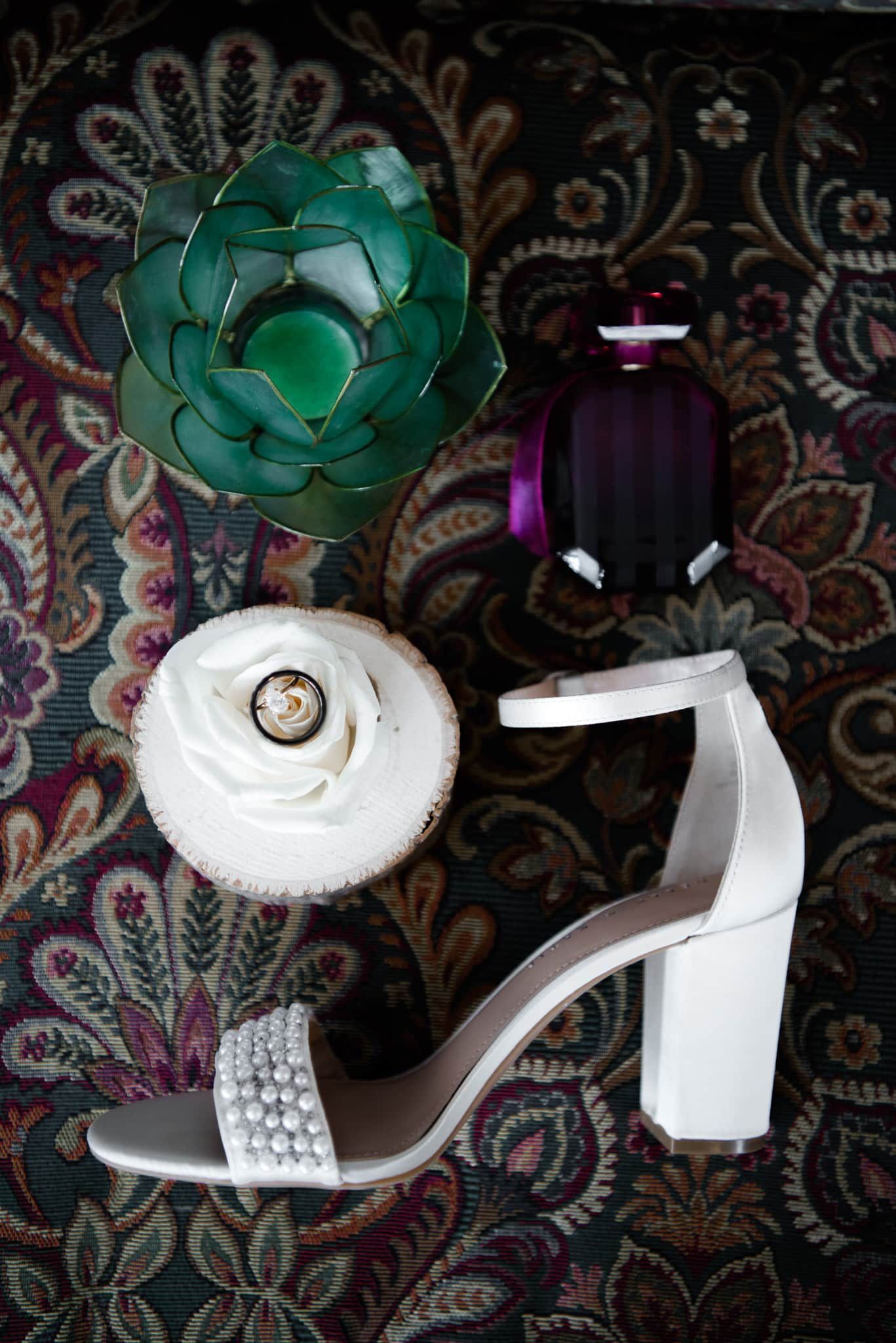 A pair of white shoes , a ring , a cupcake and a bottle of perfume