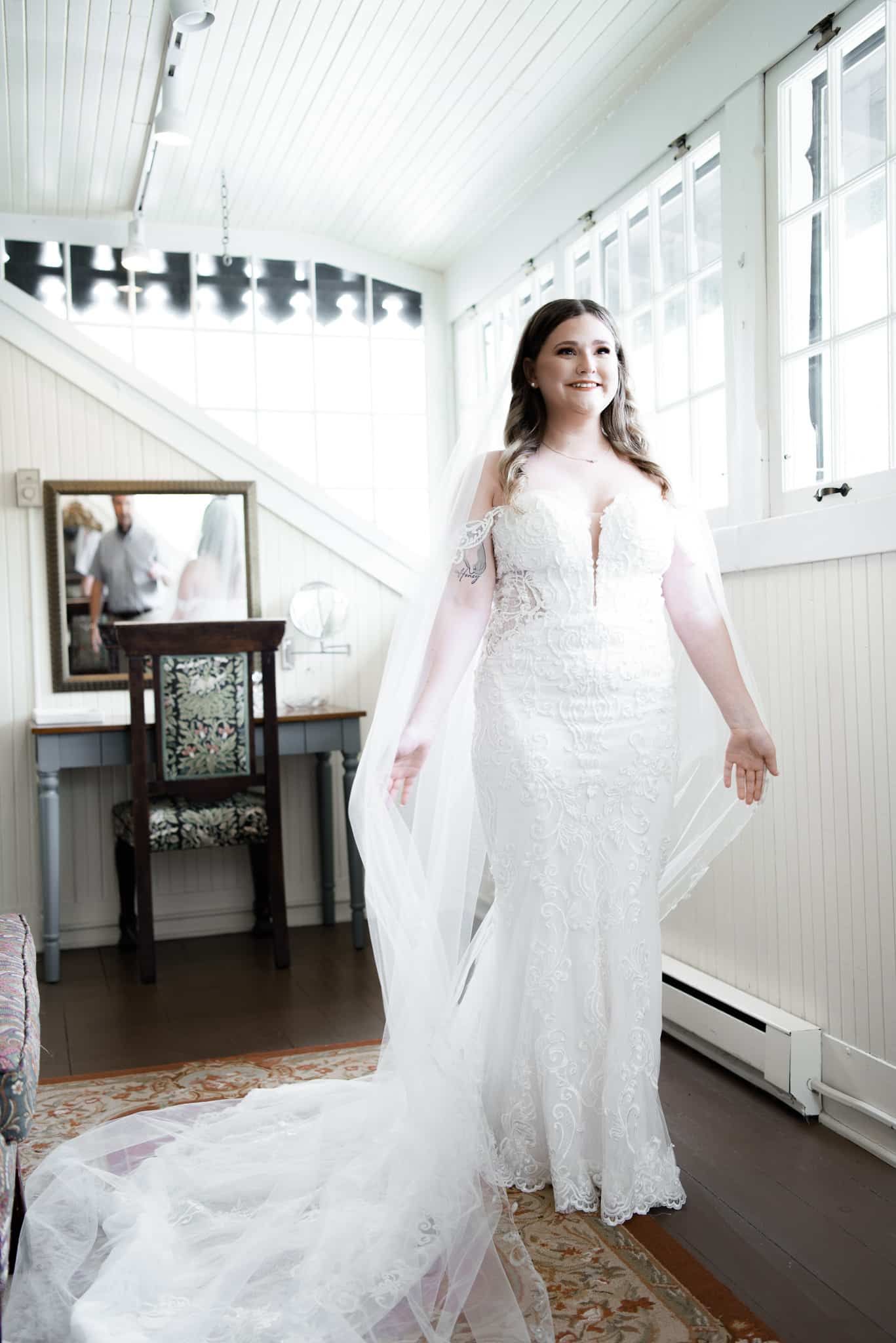 A bride in a white dress and veil is standing in a room.