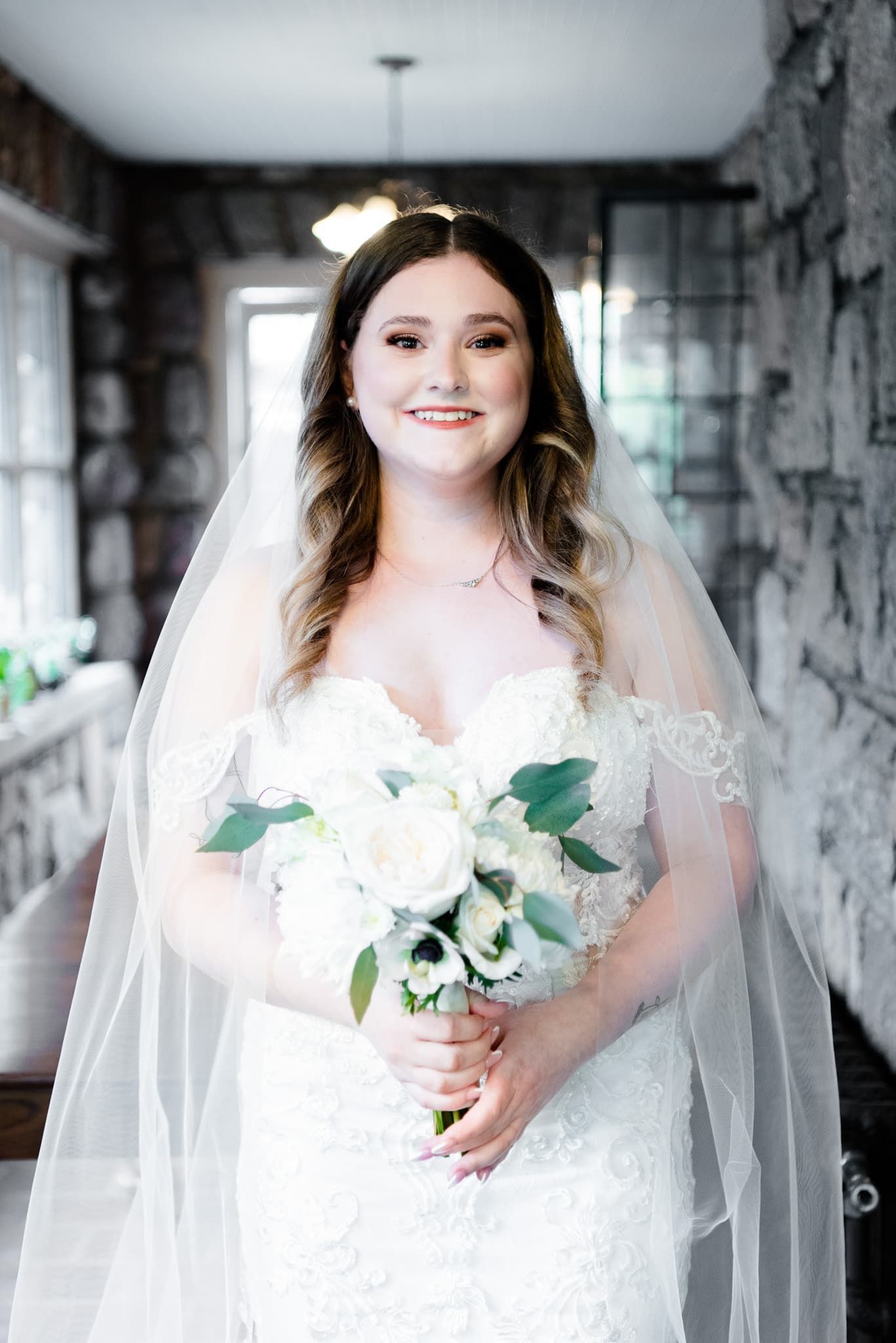 The bride is wearing a veil and holding a bouquet of white flowers.