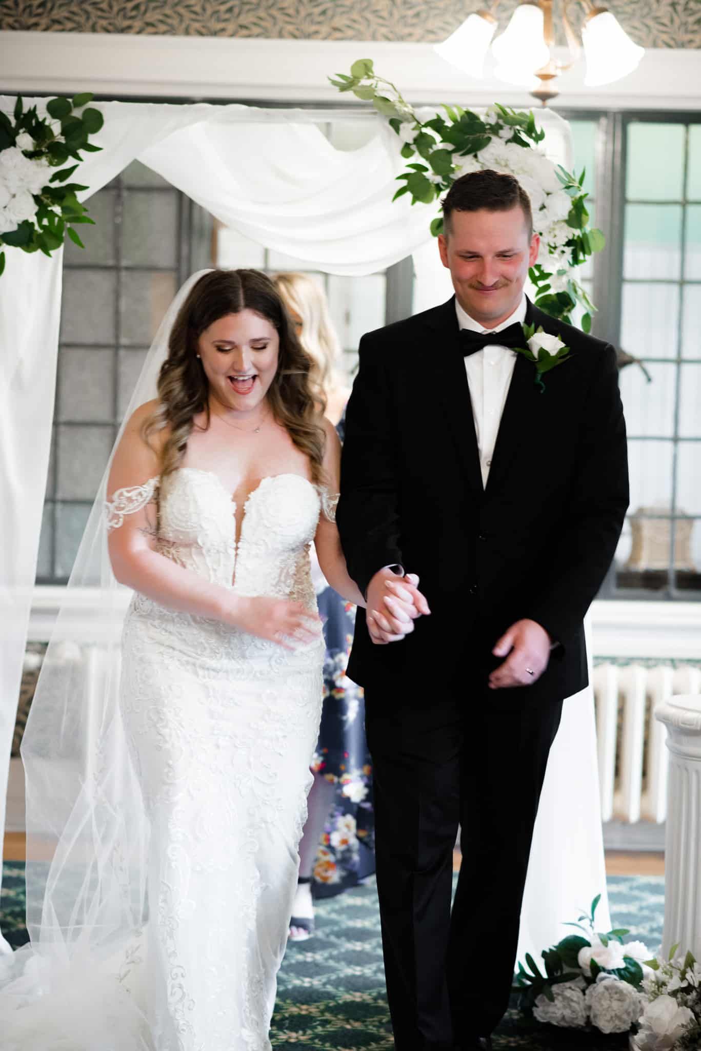 A bride and groom are walking down the aisle at their wedding holding hands.
