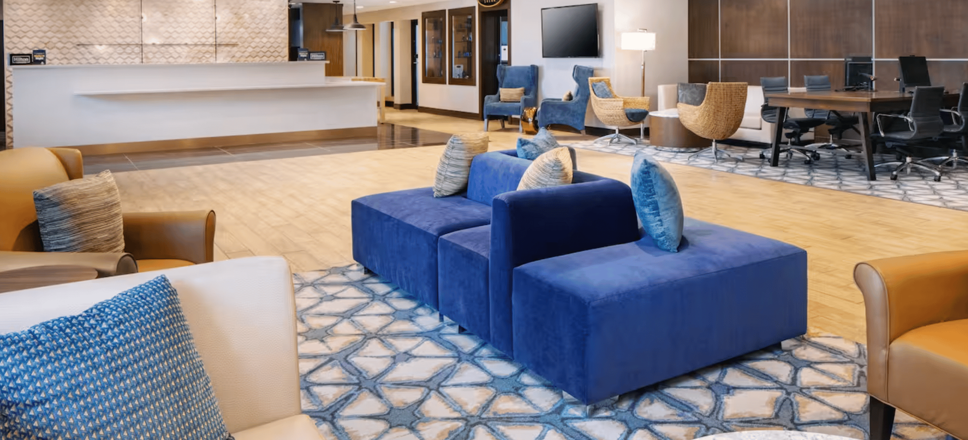 A hotel lobby with a couch , chairs , and a desk.