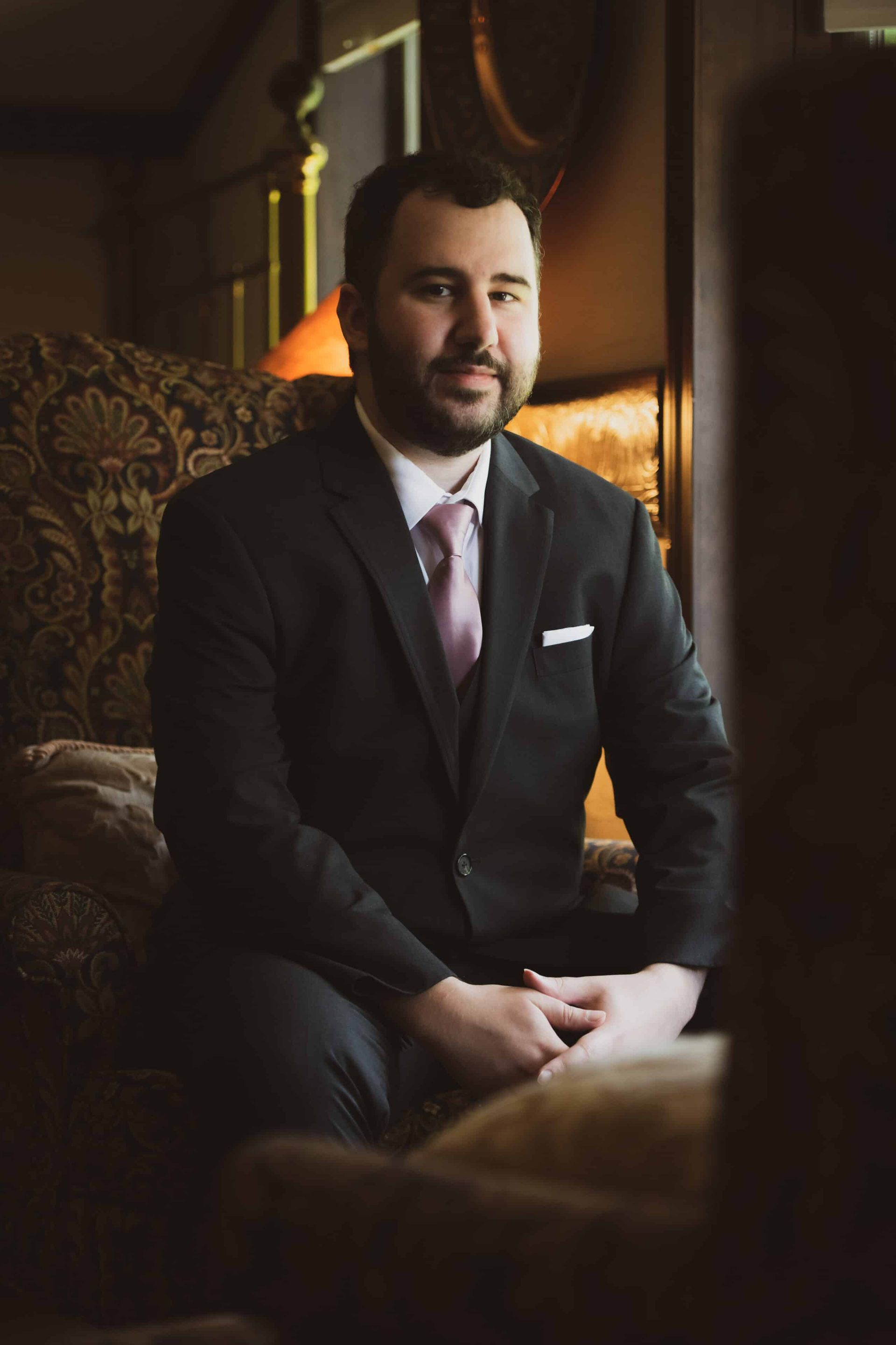 A man in a suit and tie is sitting in a chair.