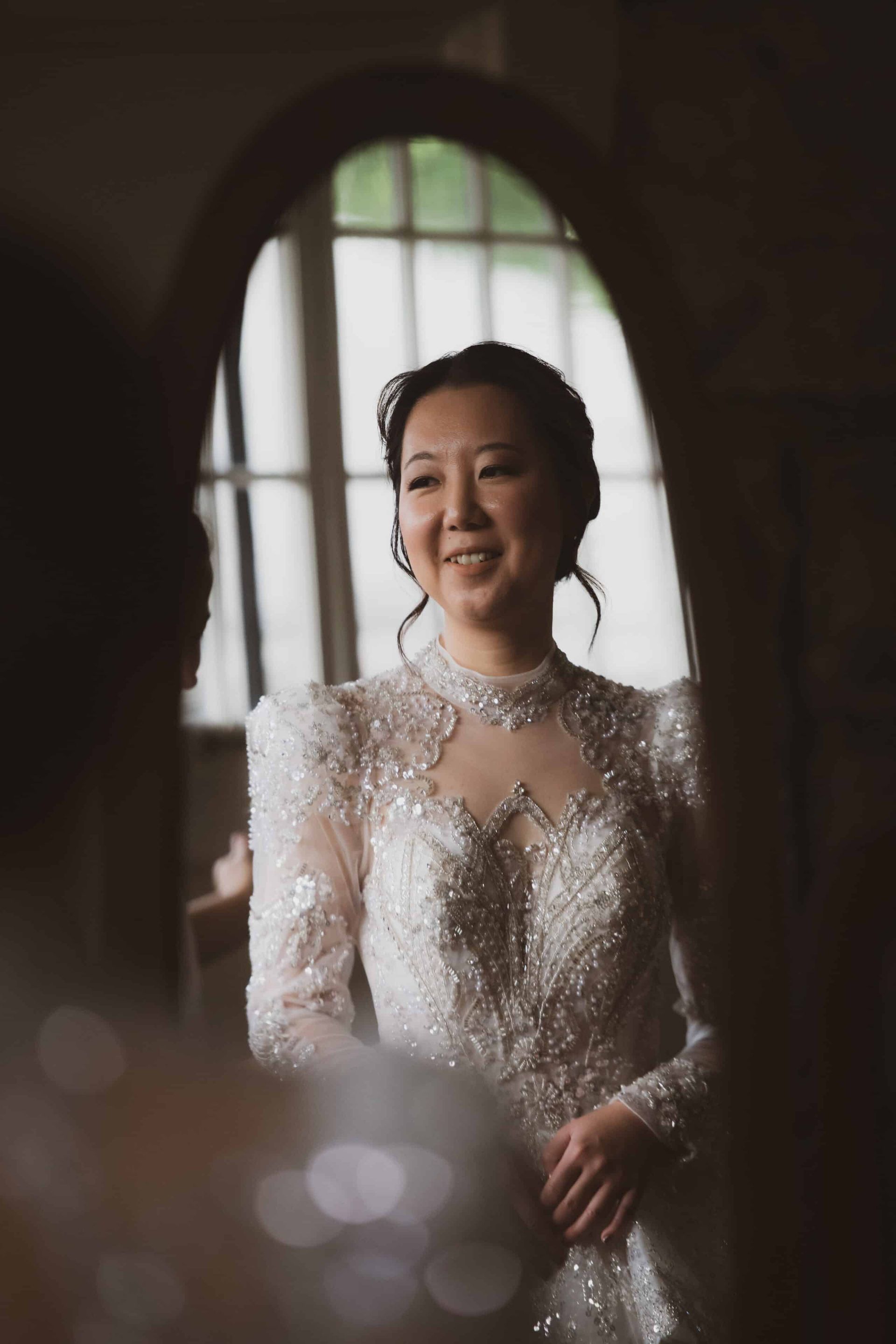 A woman in a wedding dress is looking at herself in a mirror.