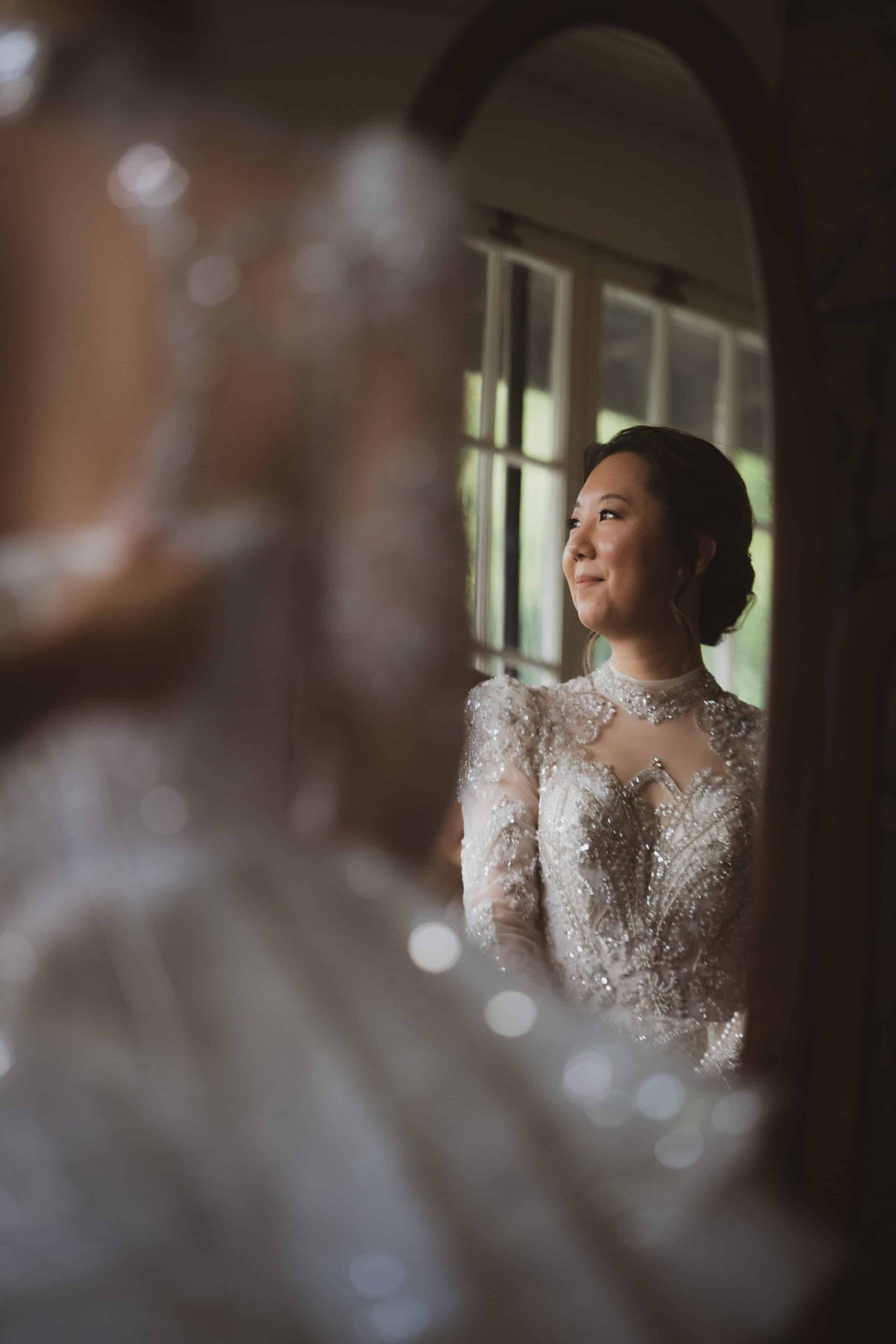 A woman in a wedding dress is looking at herself in a mirror.