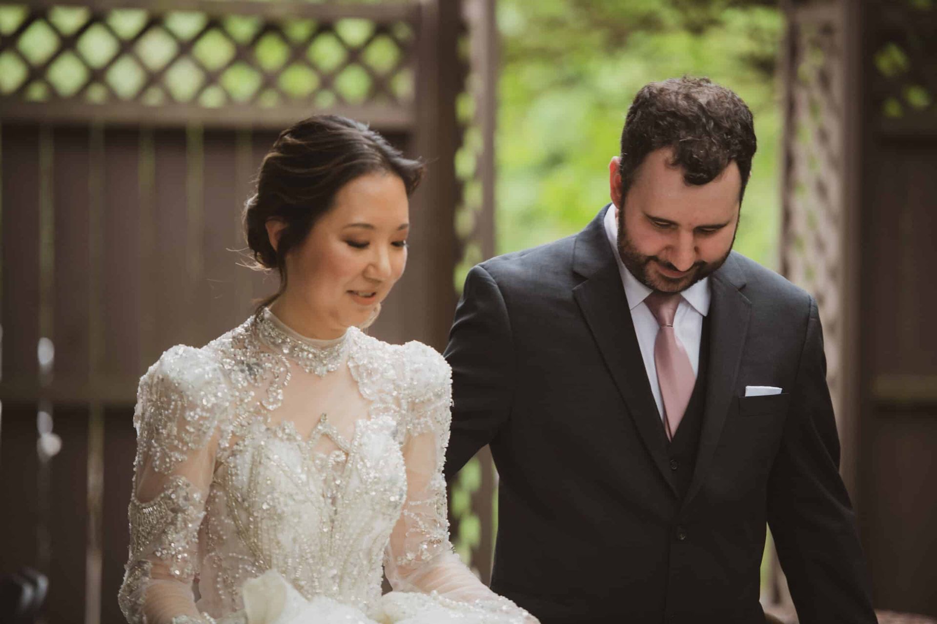 A bride and groom are standing next to each other in front of a wooden fence.