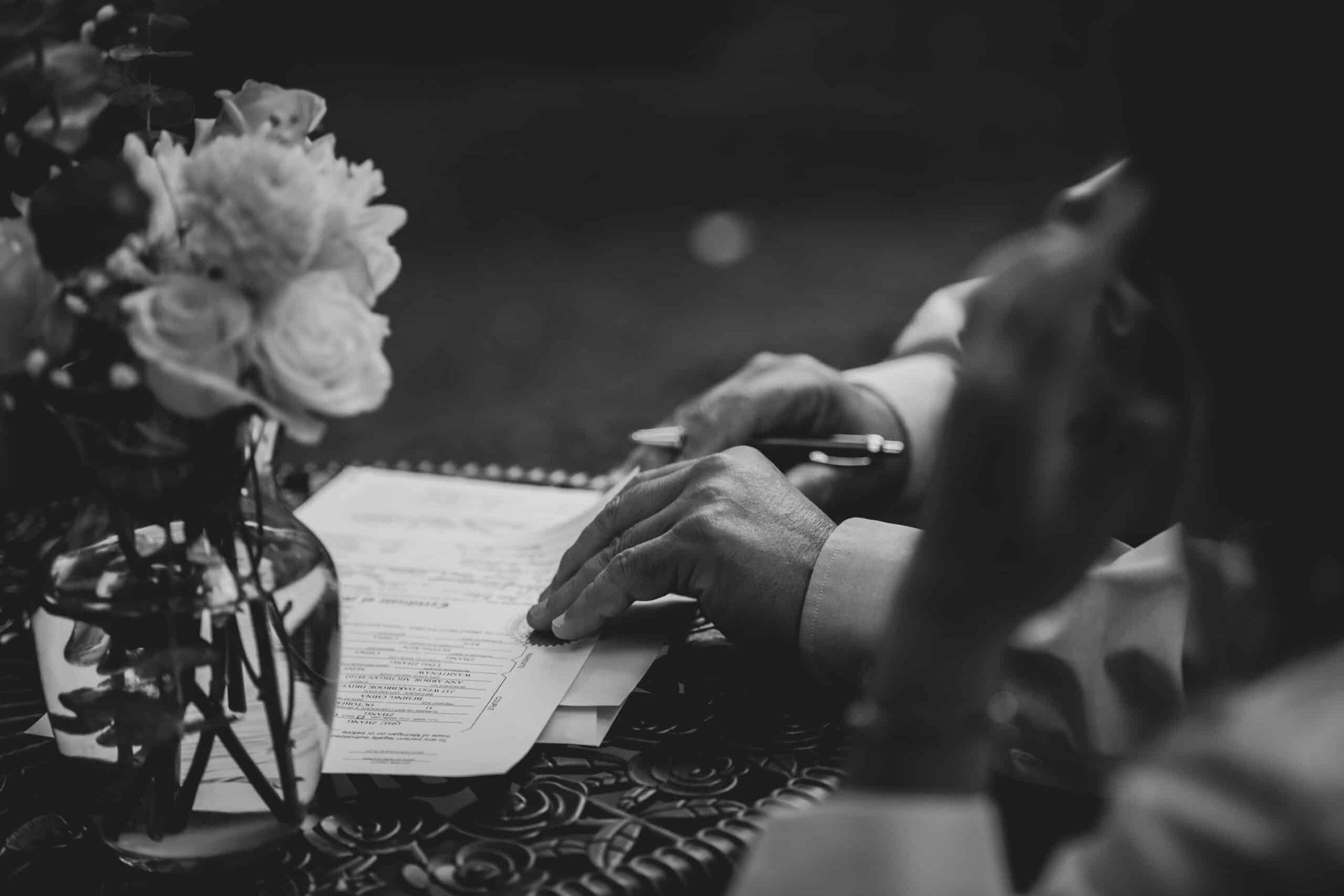 A man is sitting at a table writing on a piece of paper.
