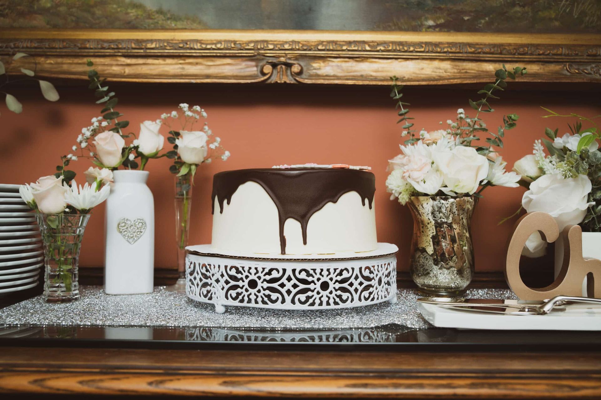 A wedding cake is sitting on a table next to vases of flowers.