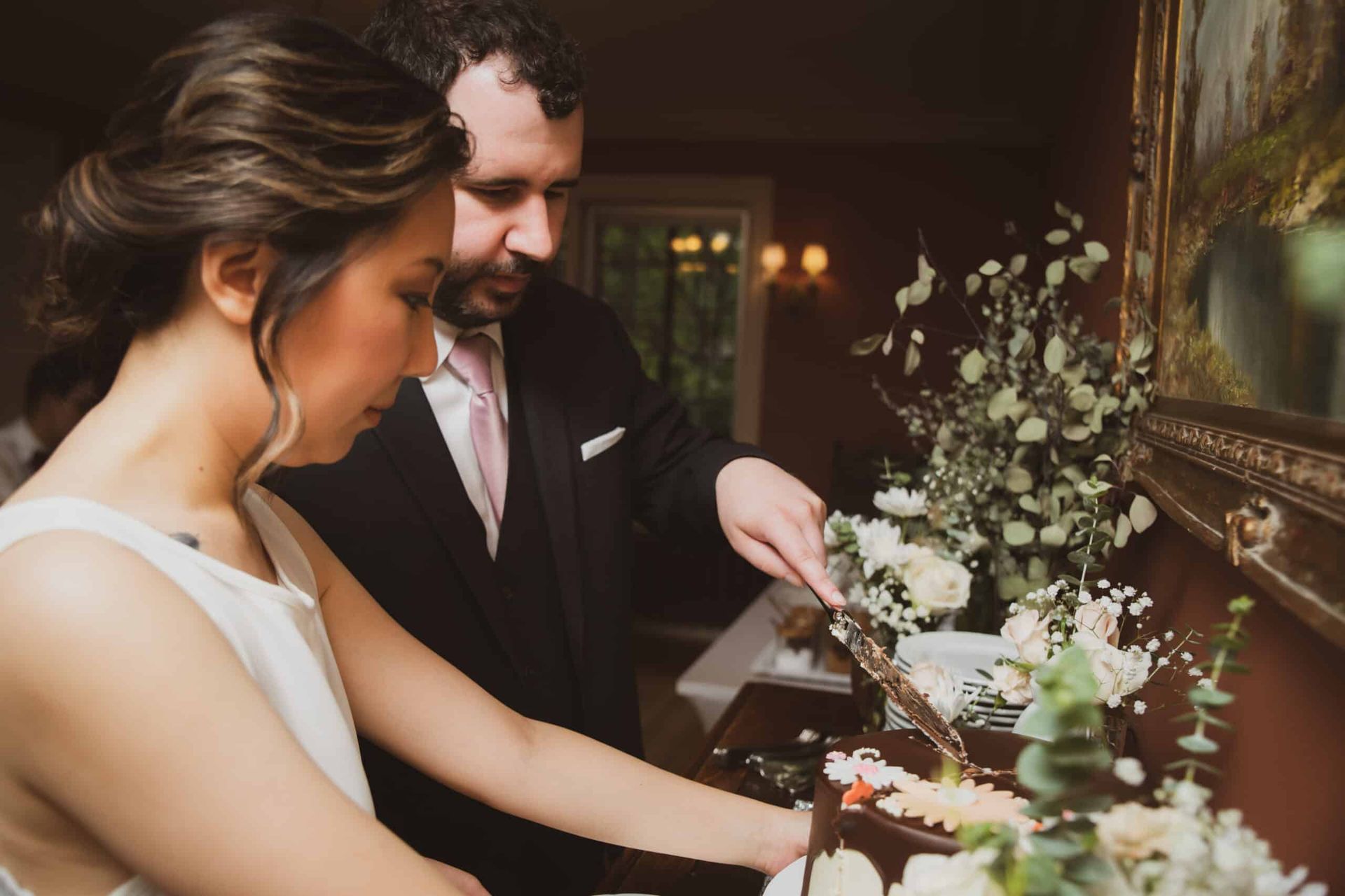 A bride and groom are cutting their wedding cake together.