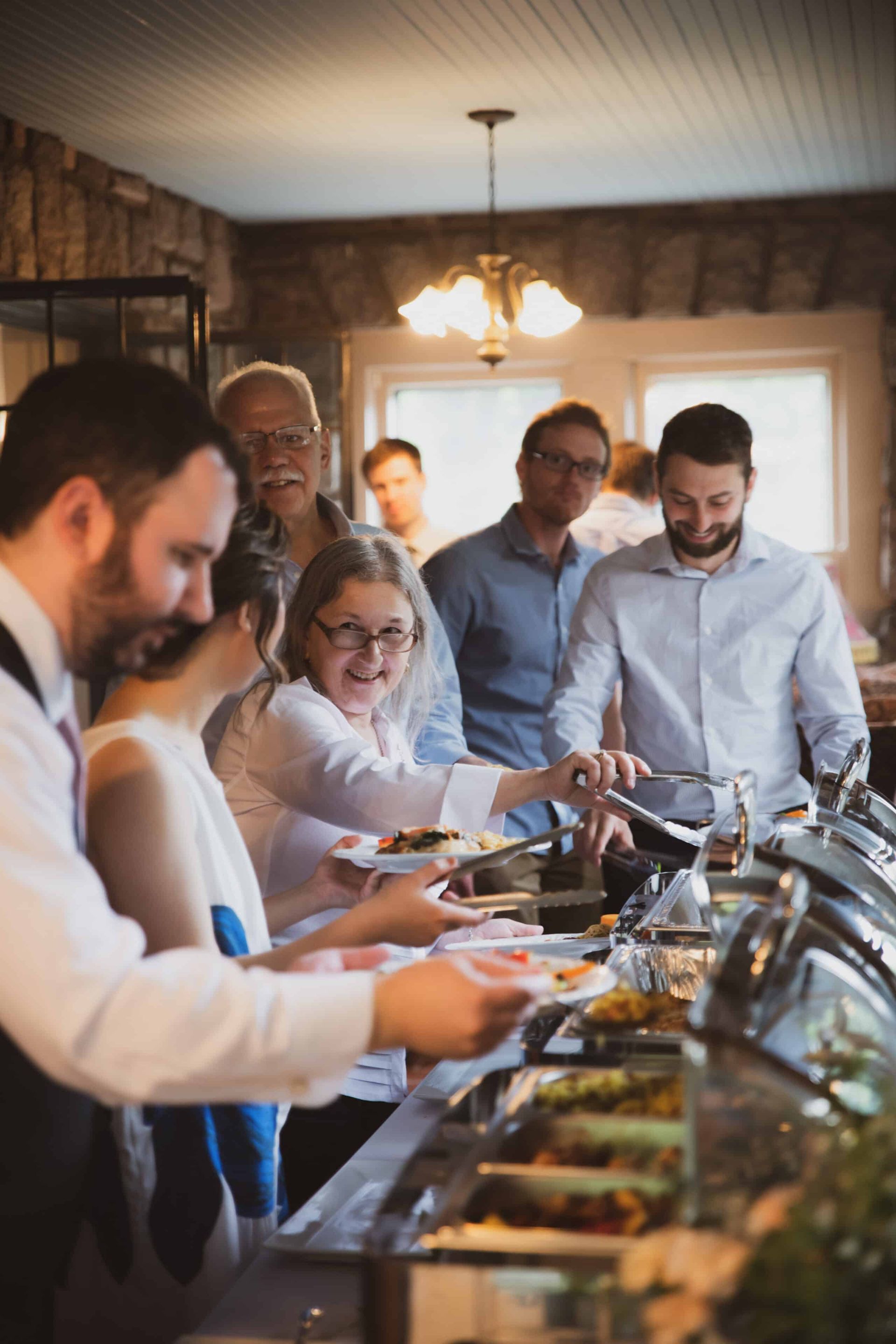 A group of people are standing in line to get food from a buffet.