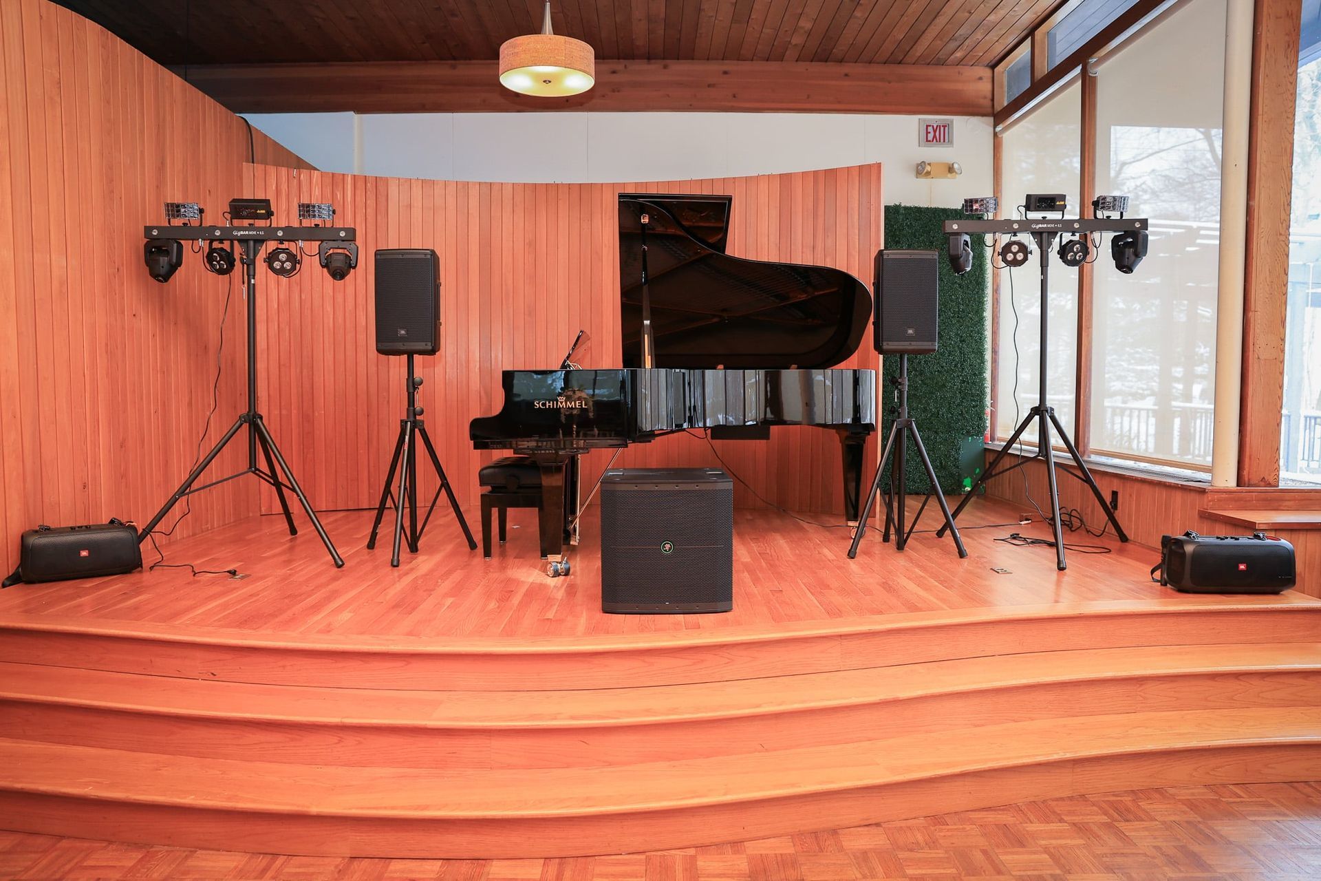 A piano is on a stage in a room with speakers and lights.