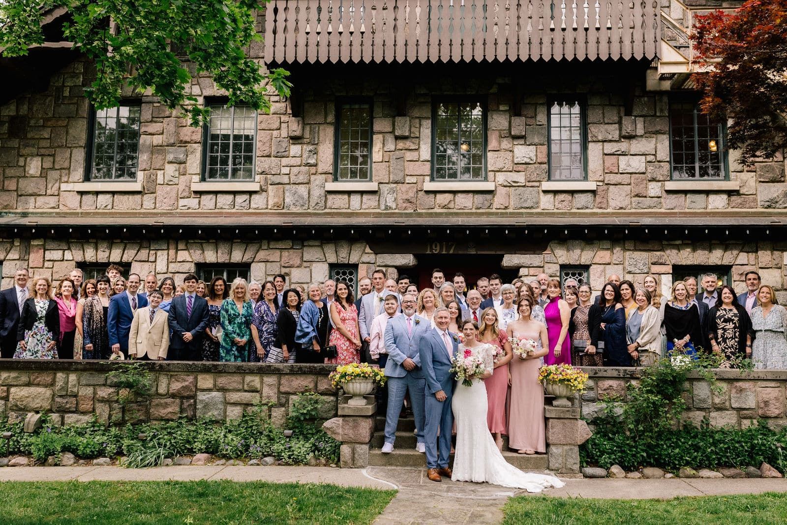 A large group of people are posing for a picture in front of a large stone building.