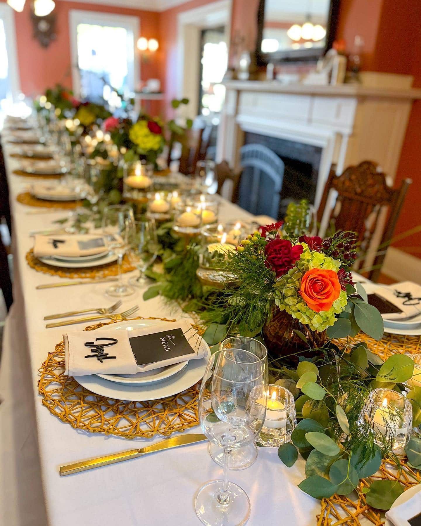 A long table with plates , candles , and flowers on it.