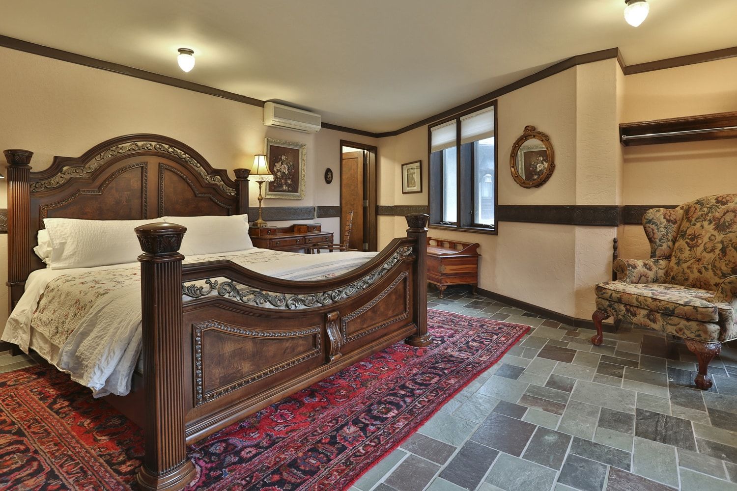 A bedroom with a king size bed , chair and rug.