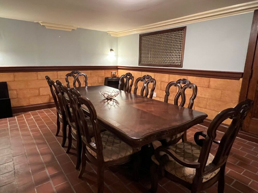 A dining room with a long wooden table and chairs