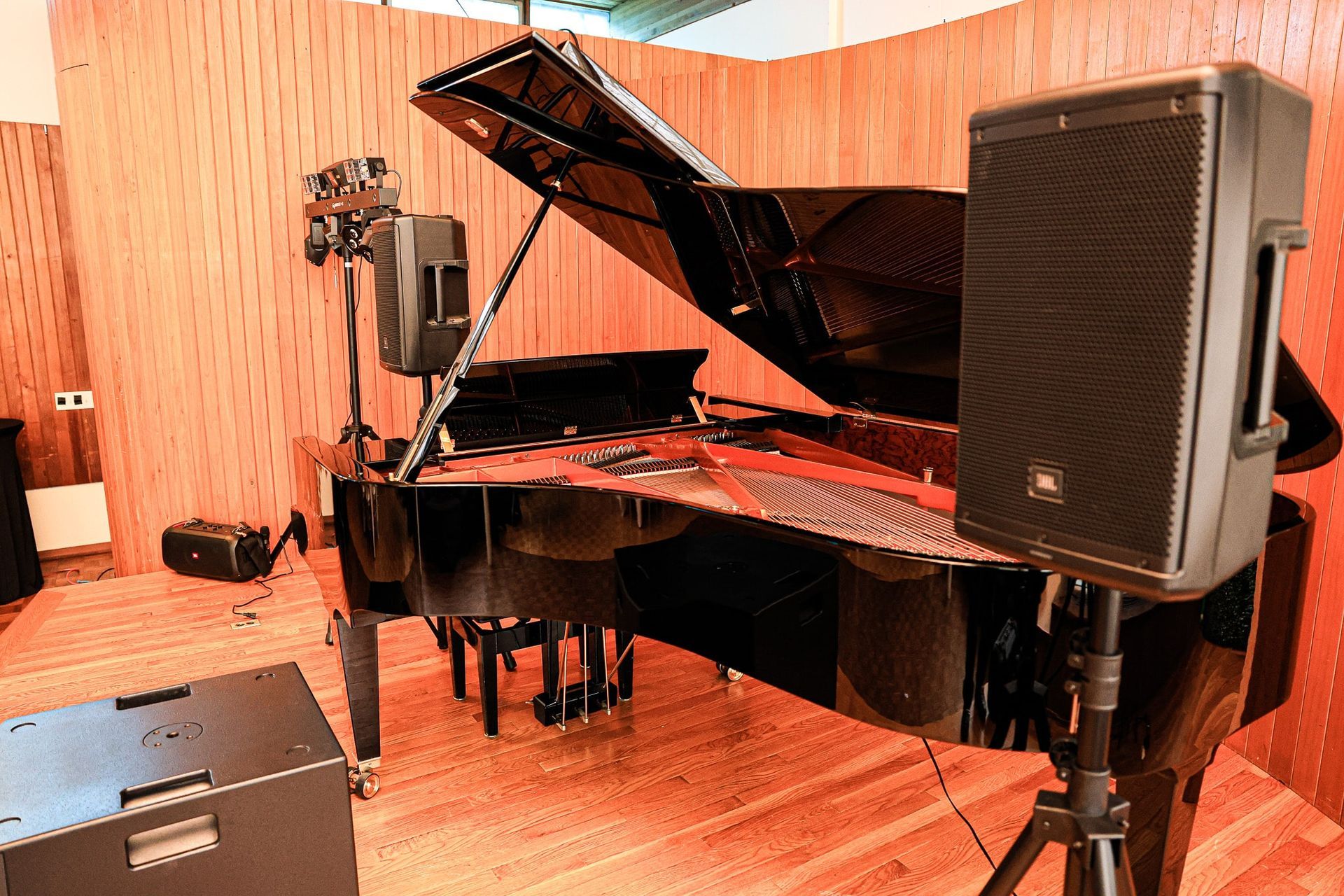 A grand piano is sitting in a room with two speakers in front of it.