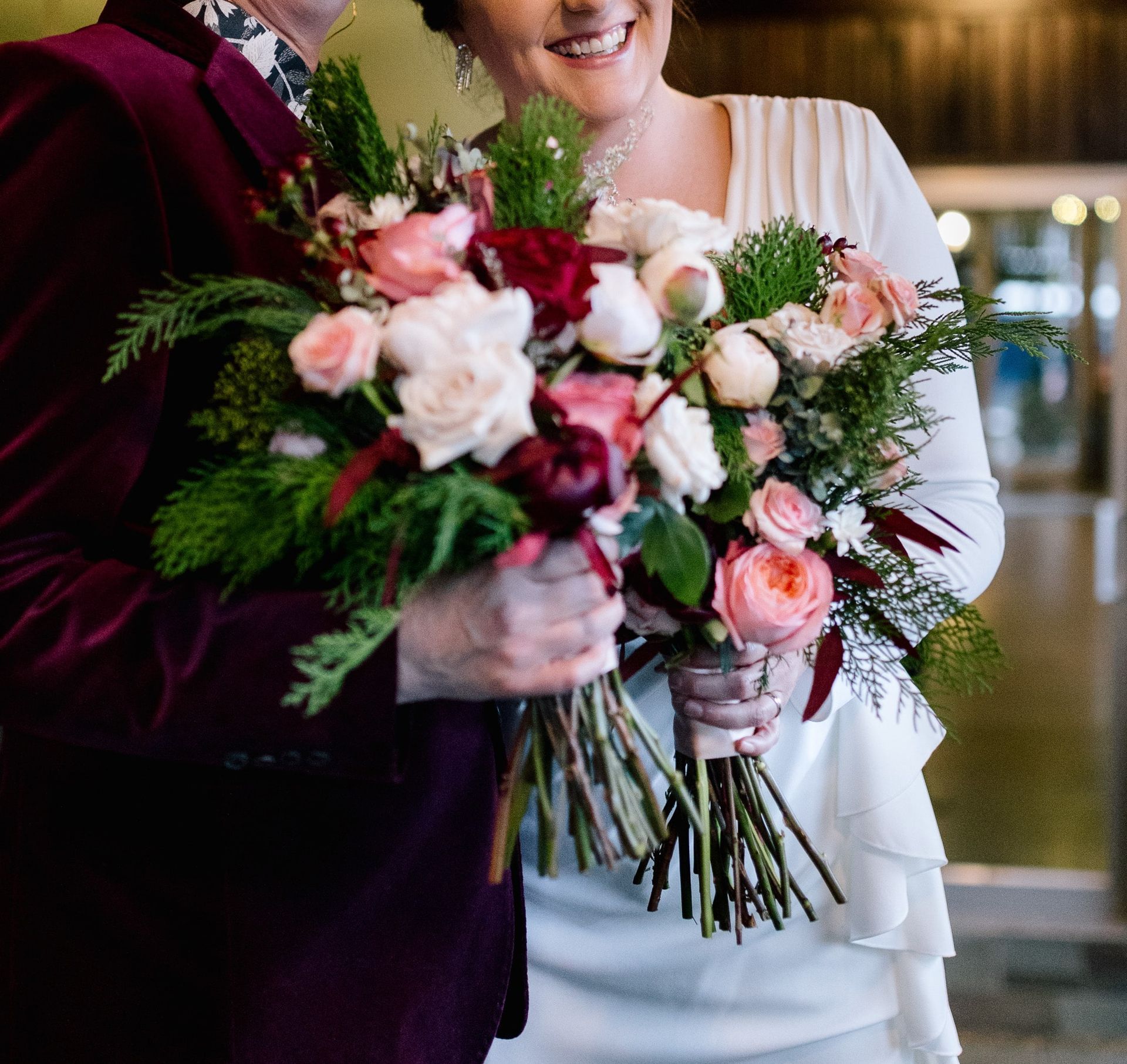 A bride and groom are holding a bouquet of flowers.