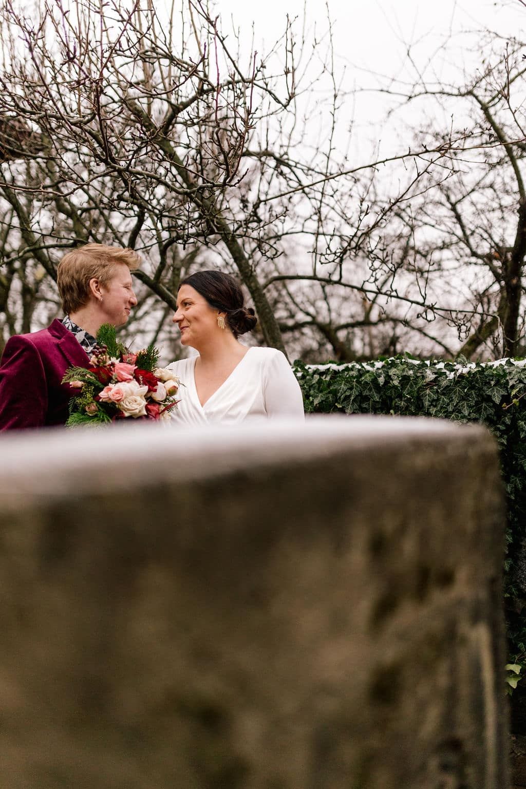 A bride and groom are standing next to each other and looking at each other.