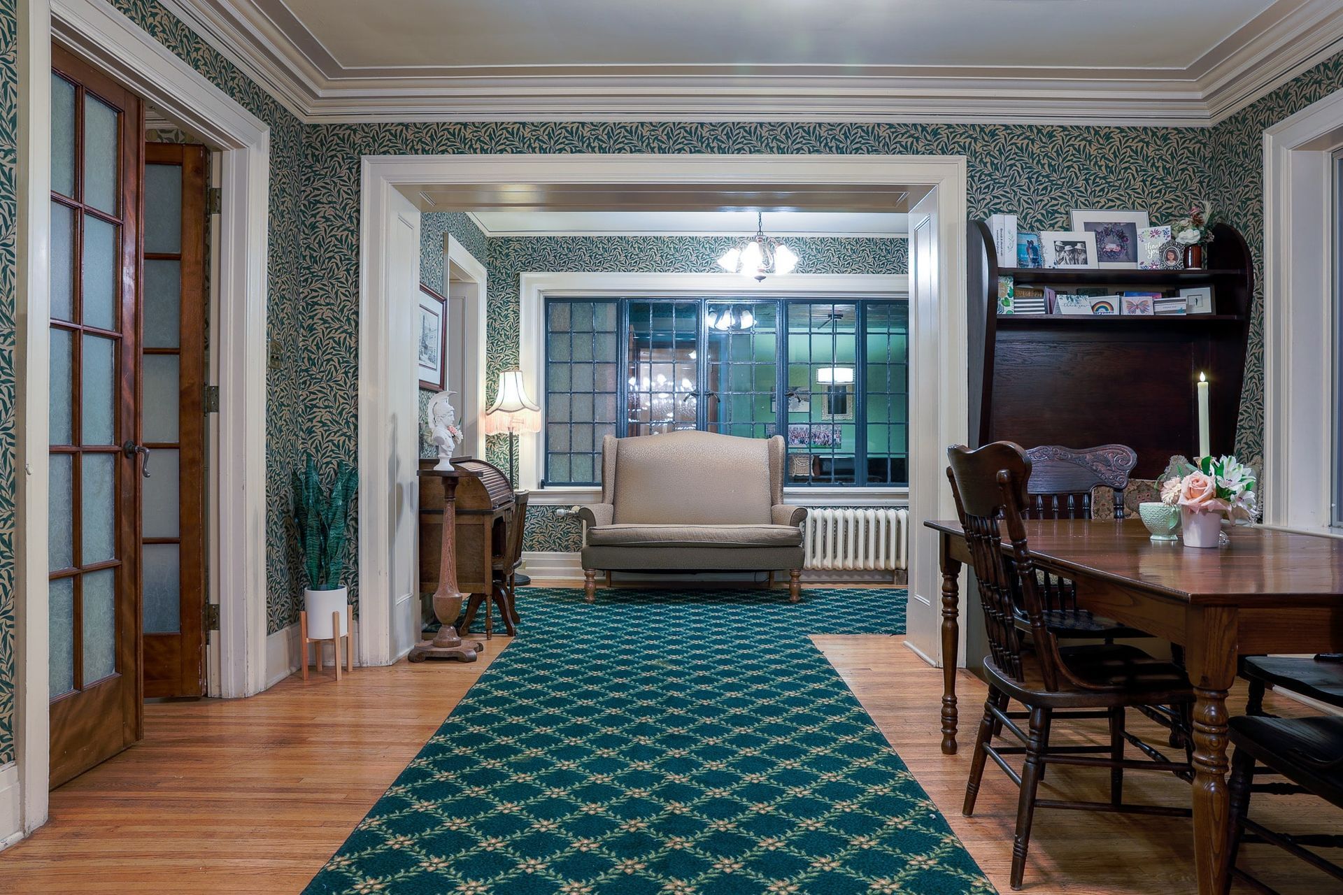 A living room with a couch , table , chairs and a green rug.