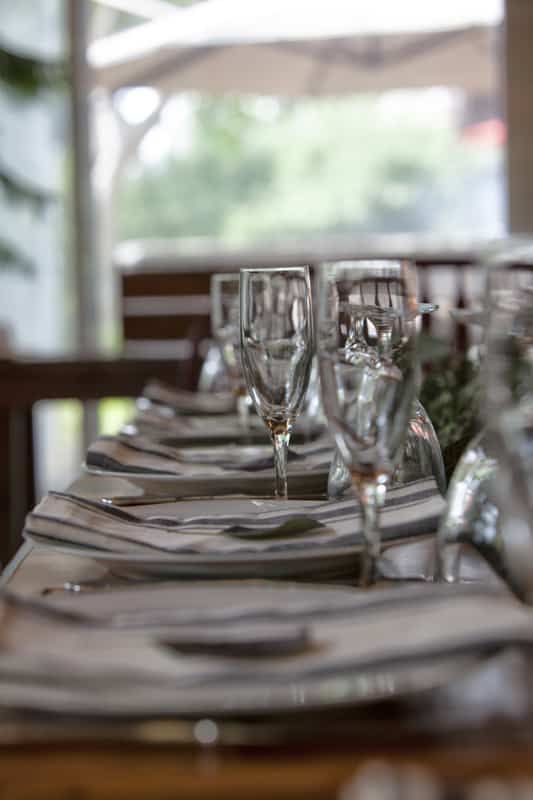 A row of wine glasses and plates on a table in a restaurant.