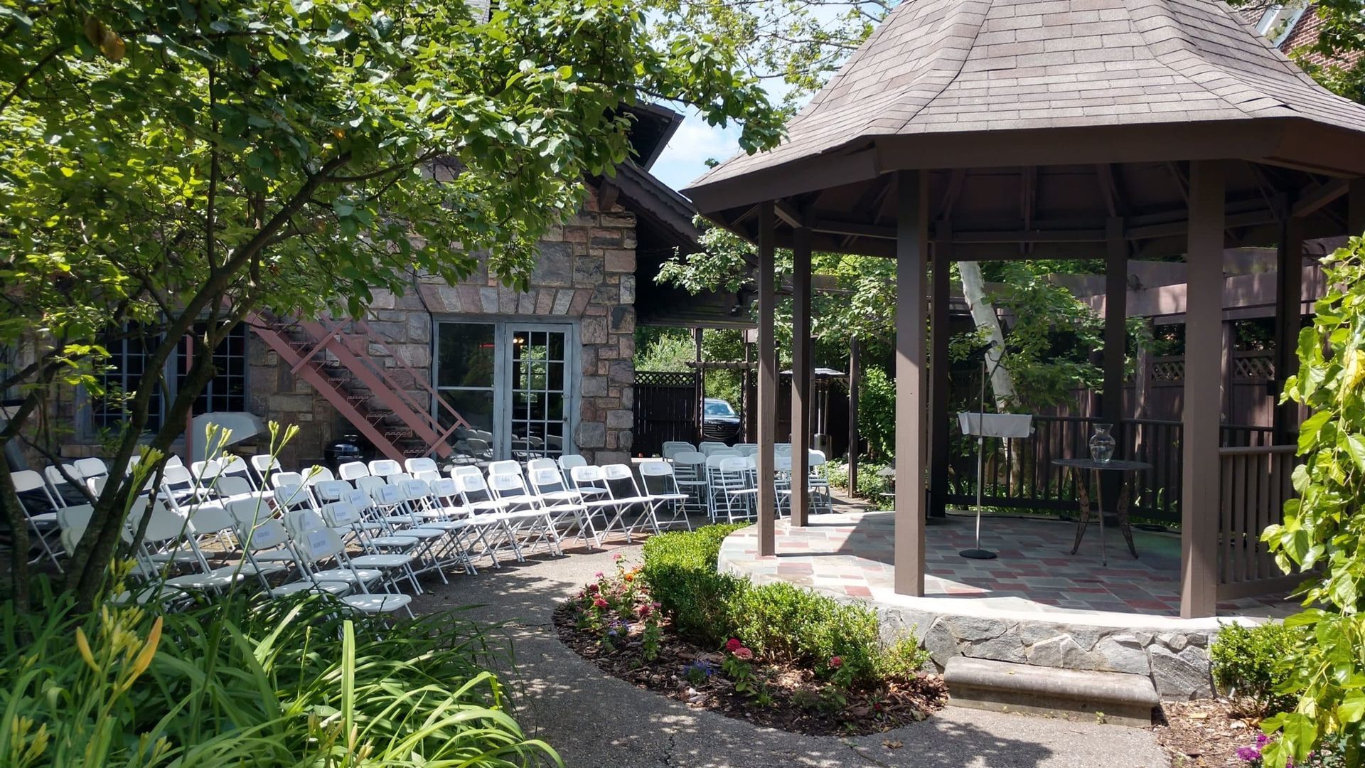 A gazebo with tables and chairs set up for a wedding ceremony.