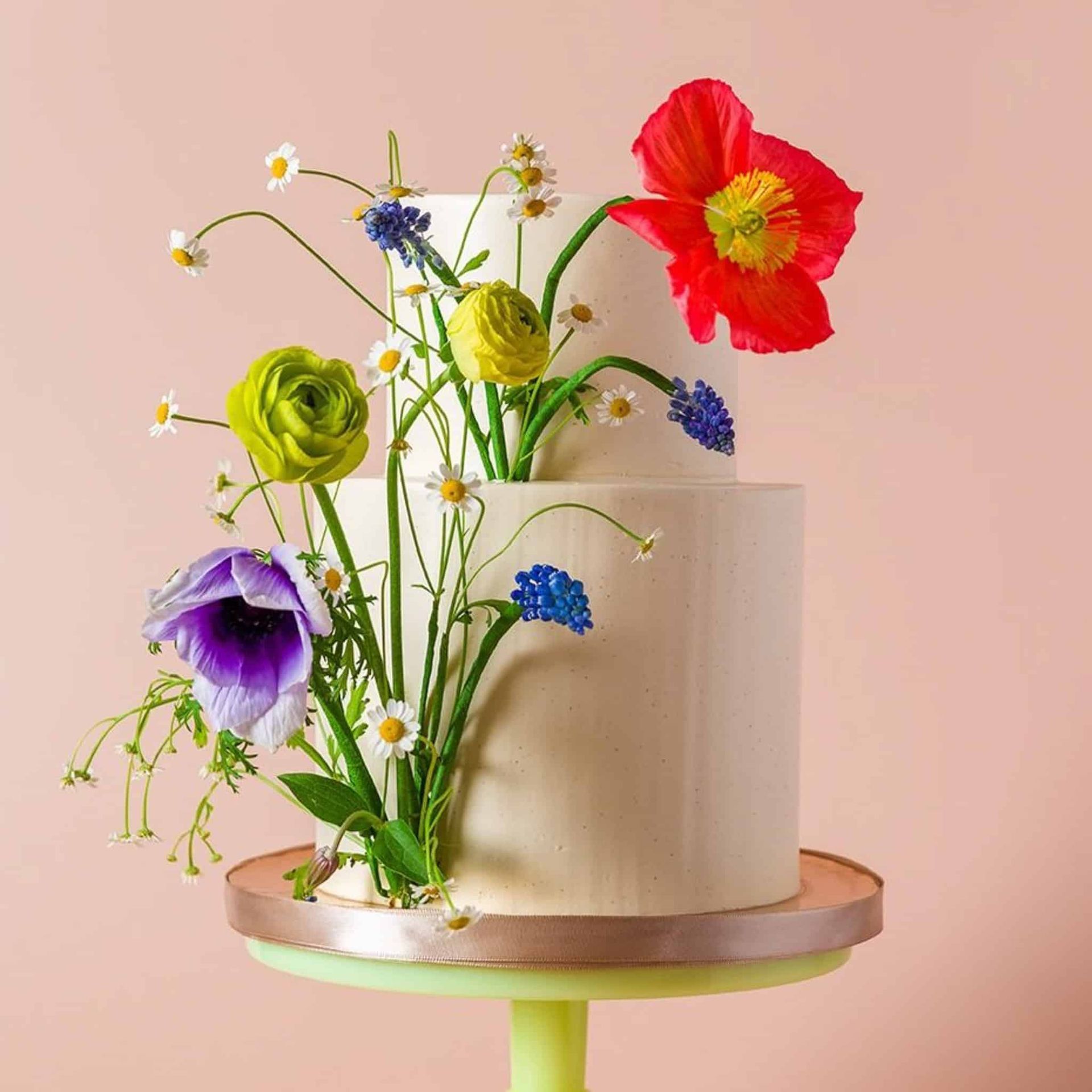 A bride and groom are posing for a picture while the bride is holding a bouquet of red flowers.